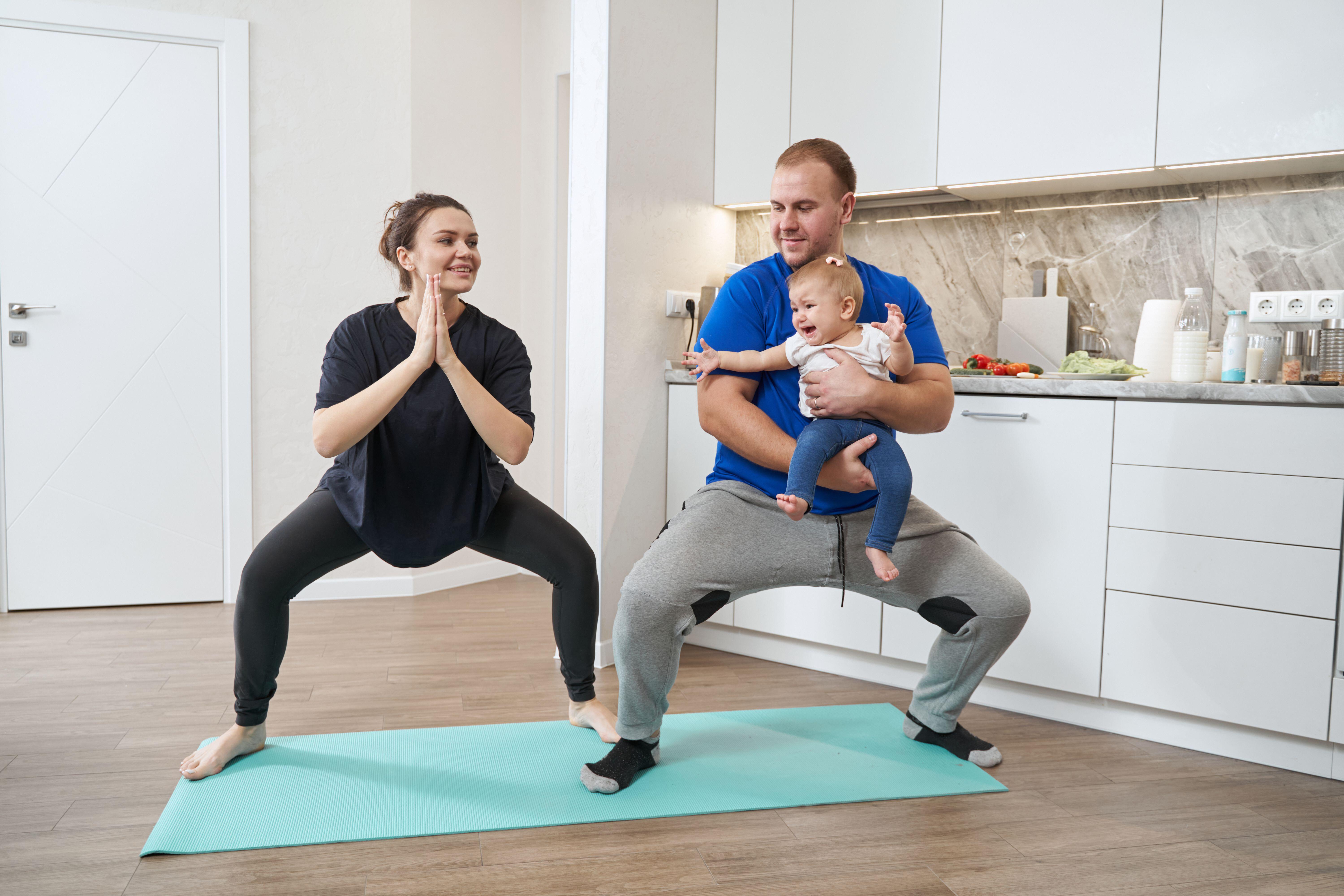 Couple with a baby doing squats at home
