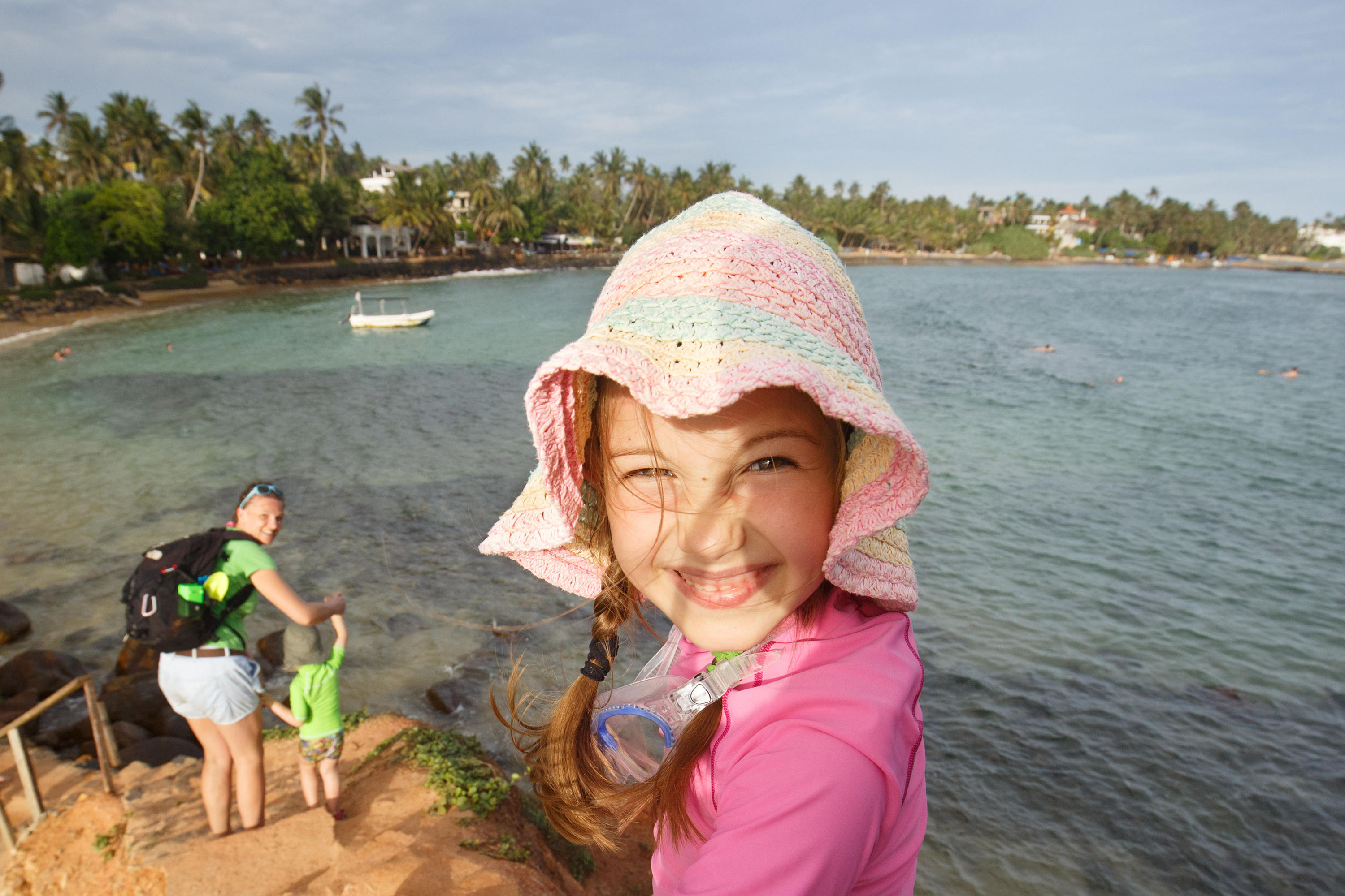 A small girl in a pink sun hat at the beach.