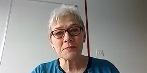 Screenshot of Henrietta Blyth from a Zoom interview. She is wearing glasses, a blue top and has short, white hair. 