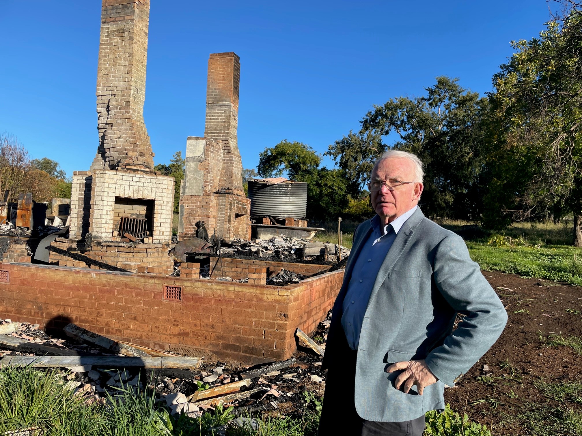 David Hill stands in front of the burnt-out remains of one of the cottages at the child migrant institution in Australia that was known as the Fairbridge Farm School, Molong