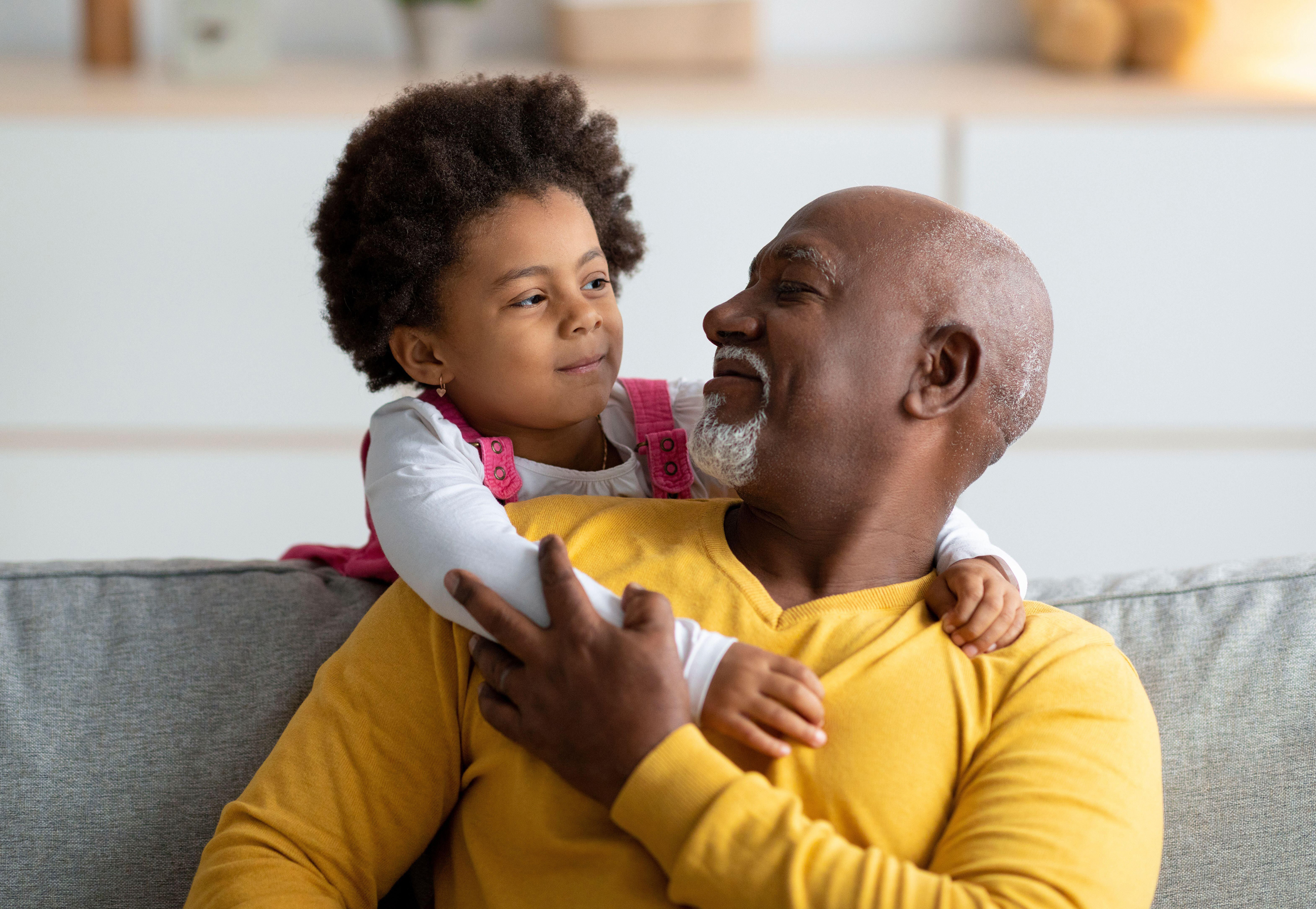 Cheerful little girl playing with older grandfather 