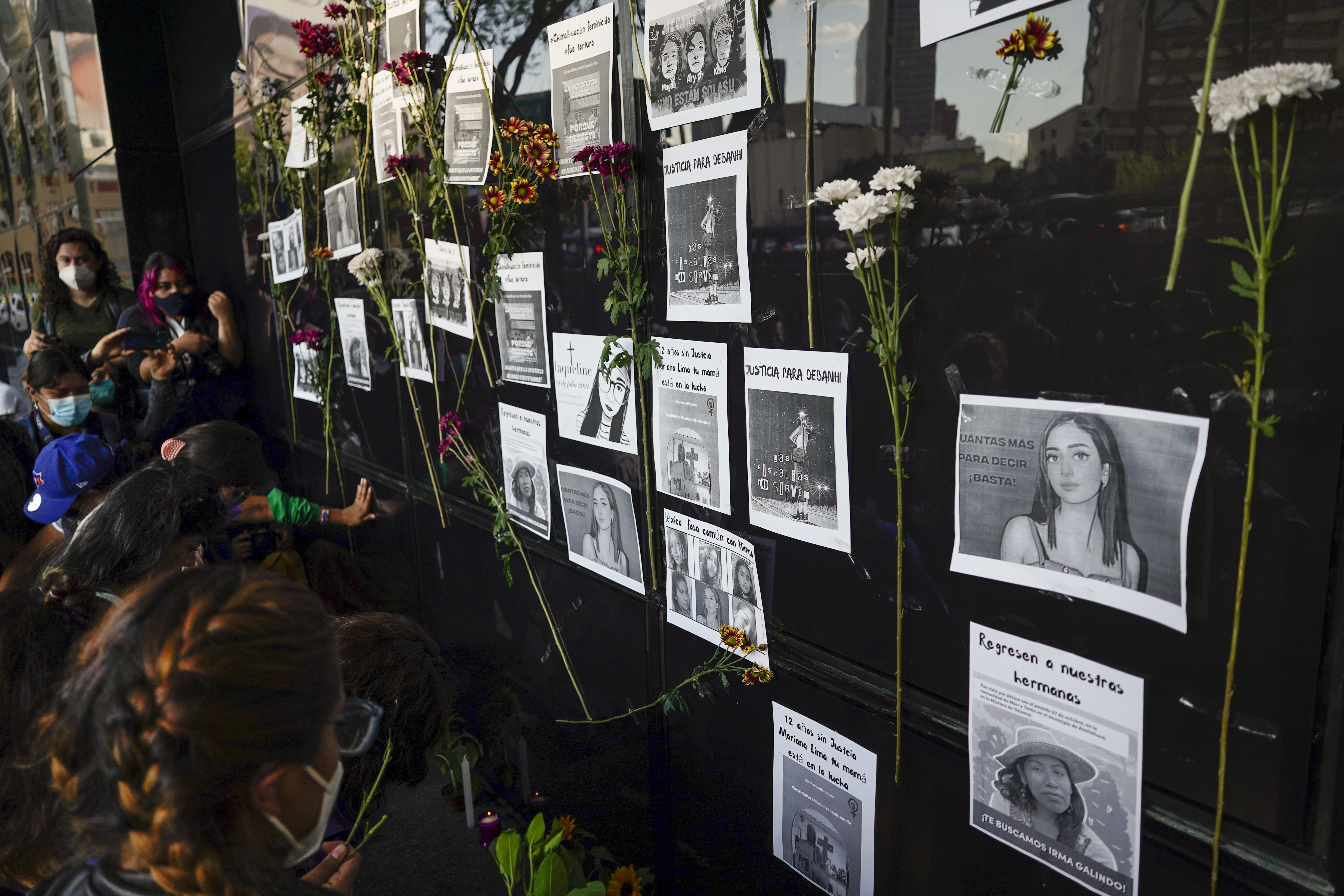 Flowers on the facade of the Attorney General's office surround images of Debanhi Escobar, right center, and other missing women, during a protest against femicide, in Mexico City, Friday, April 22, 2022
