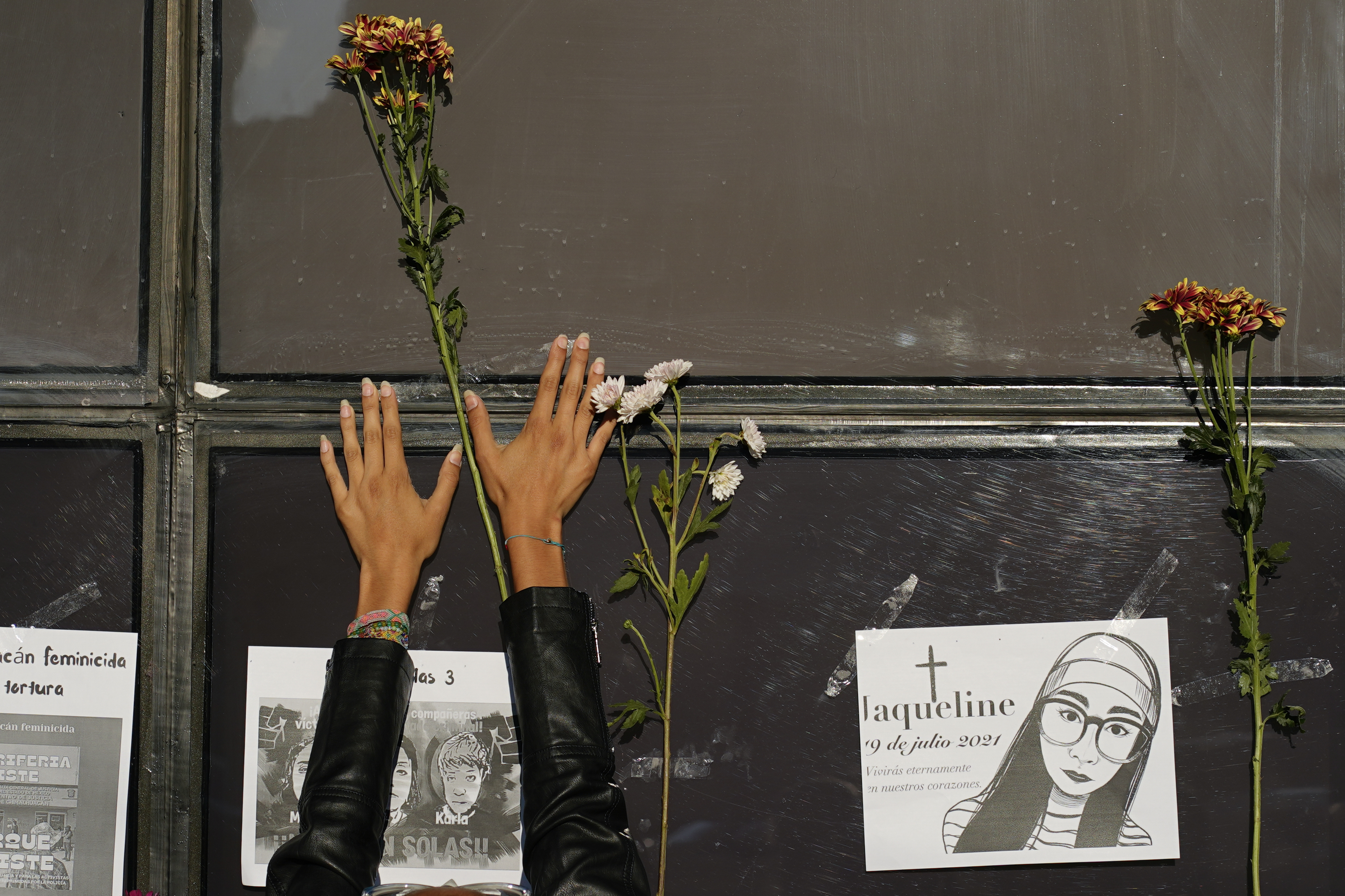 A woman places a stem of flowers on the facade of the Attorney General's office during a protest against the disappearance of Debanhi Escobar and other women who have gone missing, in Mexico City