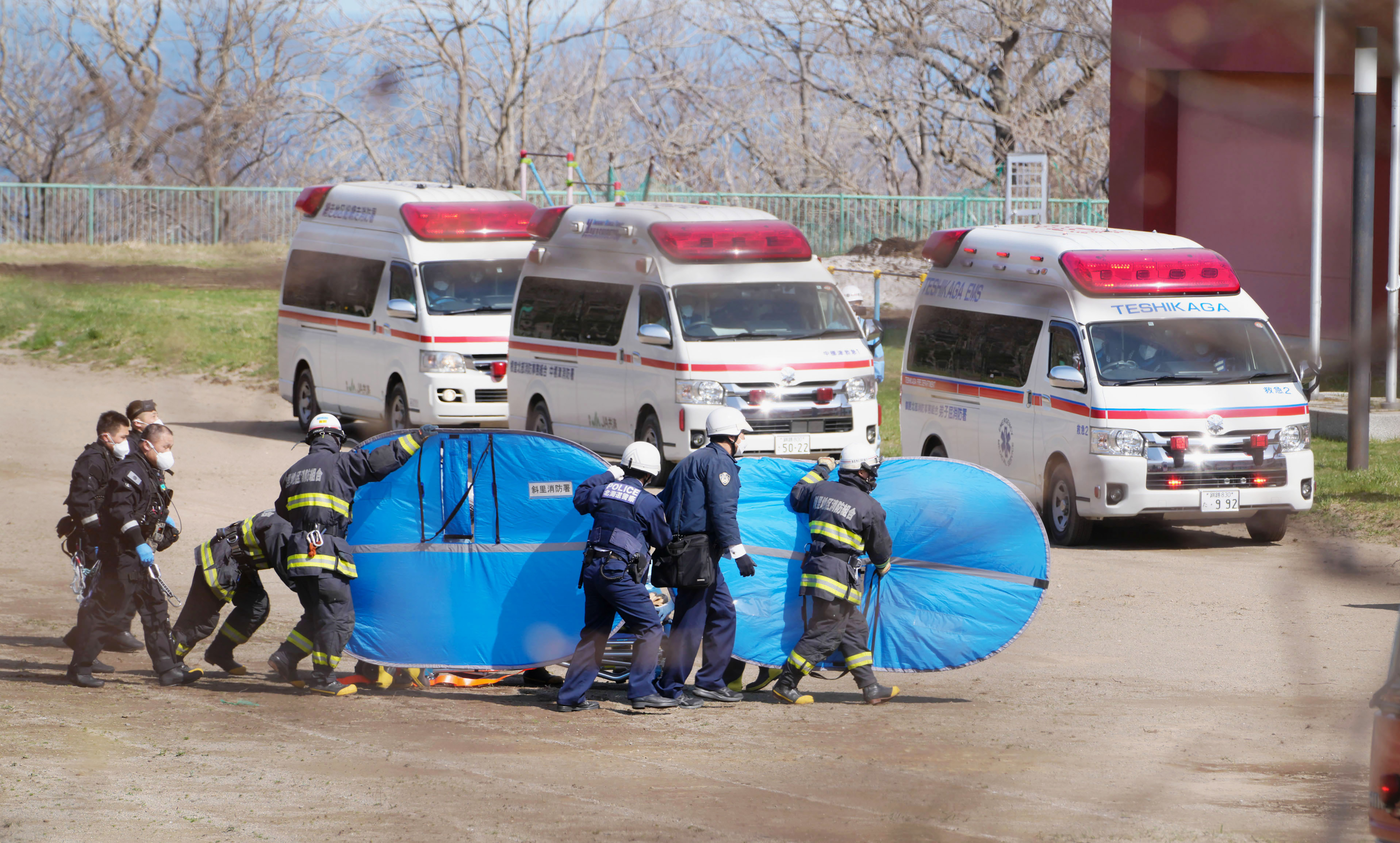 Firefighters transfer a rescued person in Shari, in the northern island of Hokkaido Sunday, April 24, 2022. The Japanese Coast Guard said Sunday that rescue helicopters found four of the 26 people on a tour boat missing in the frigid waters of northern Japan since the day before, but their conditions are unknown.