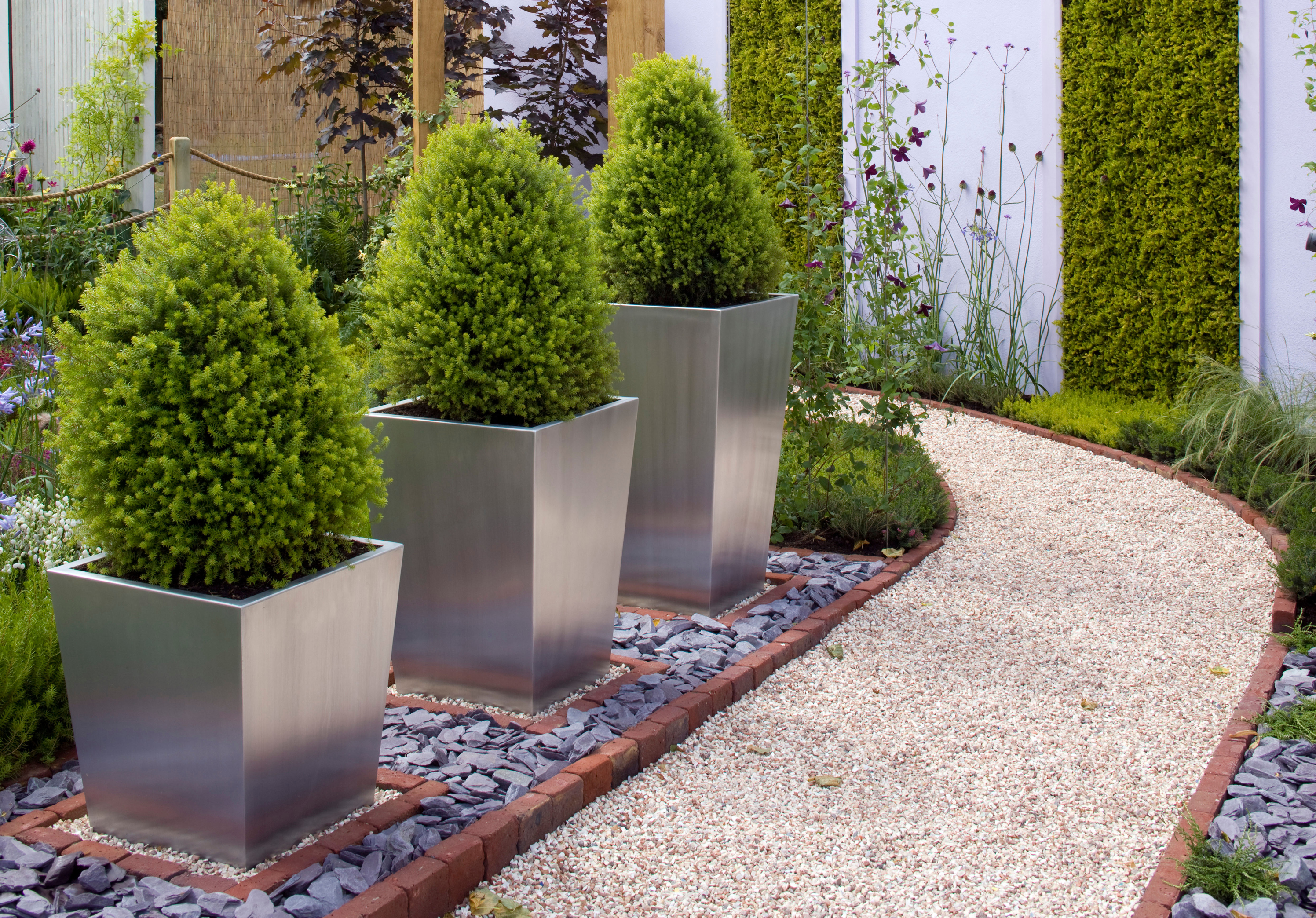 A neat front garden with evergreens in metal planters (Alamy/PA)