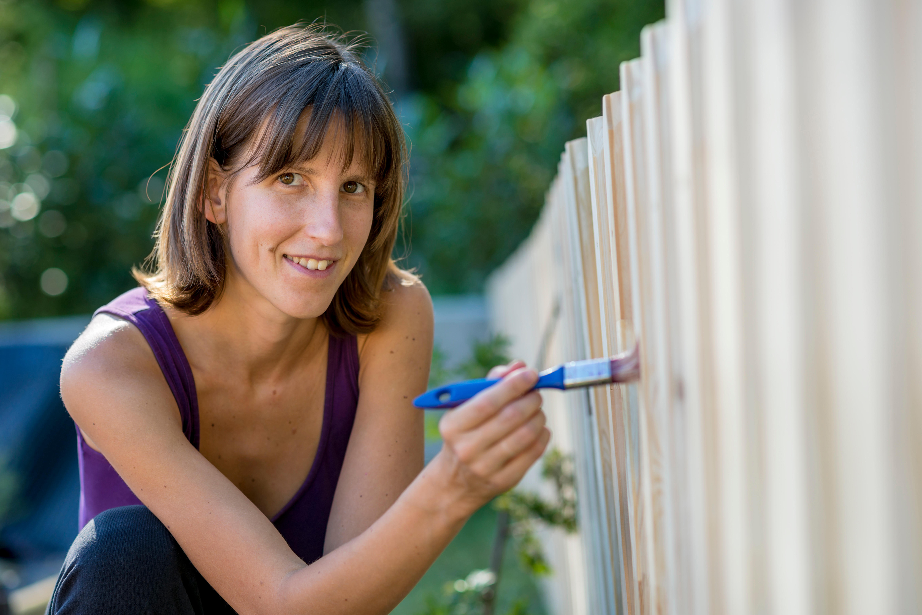 A woman painting a garden fence (Alamy/PA)