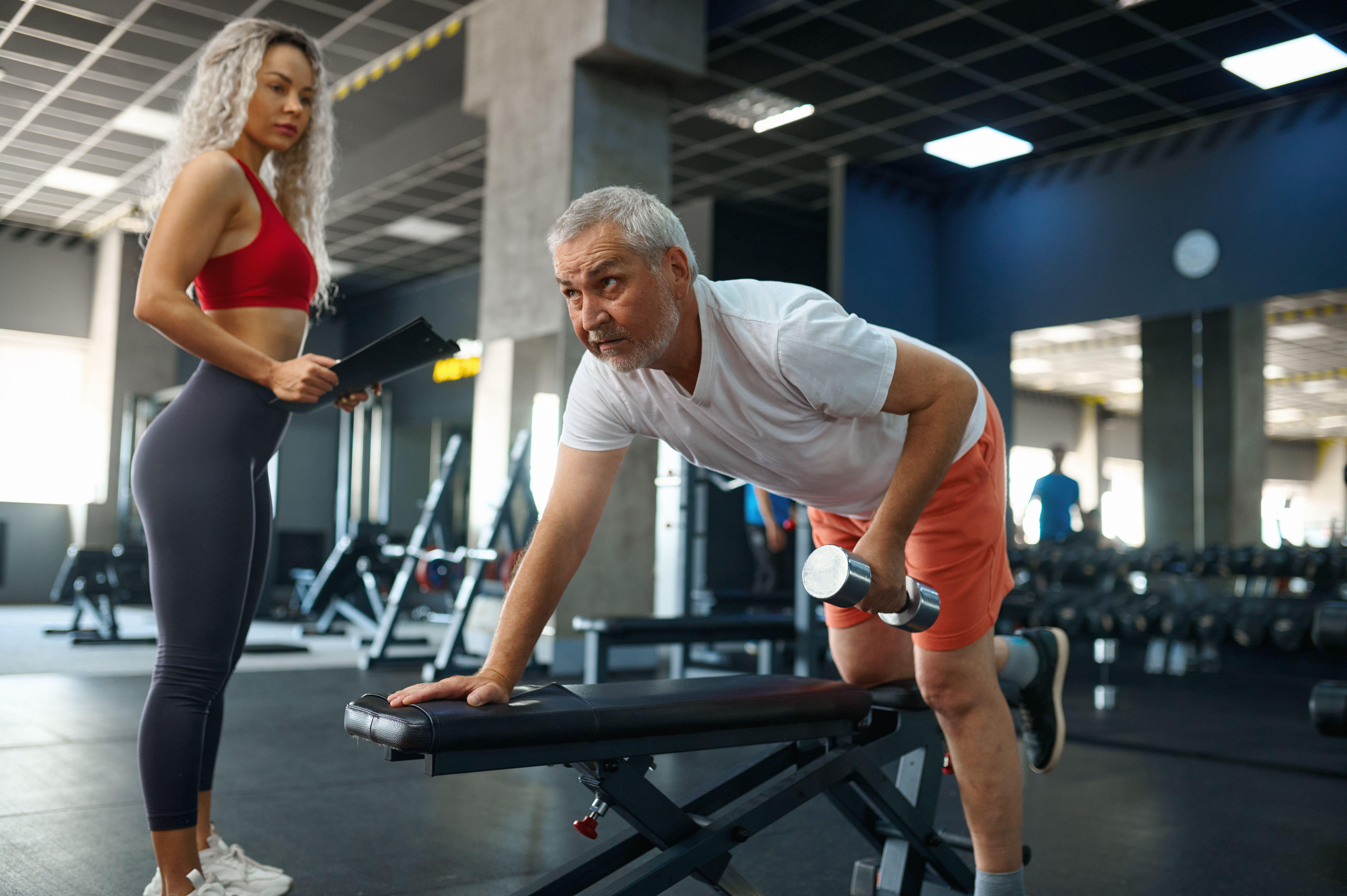 Man using dumbbels in the gym with a trainer