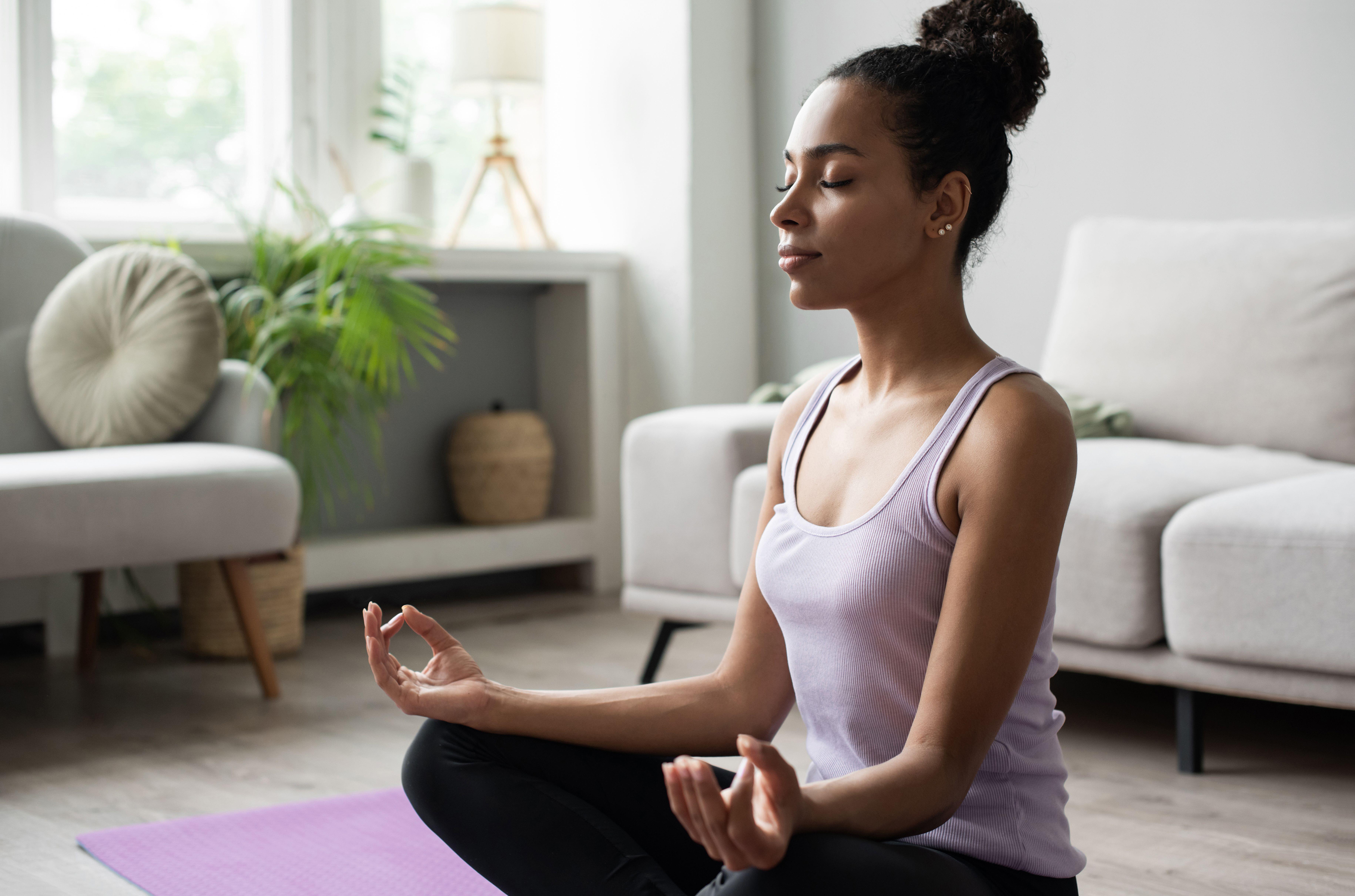 Woman sitting on the floor at home, doing deep breathing exercises