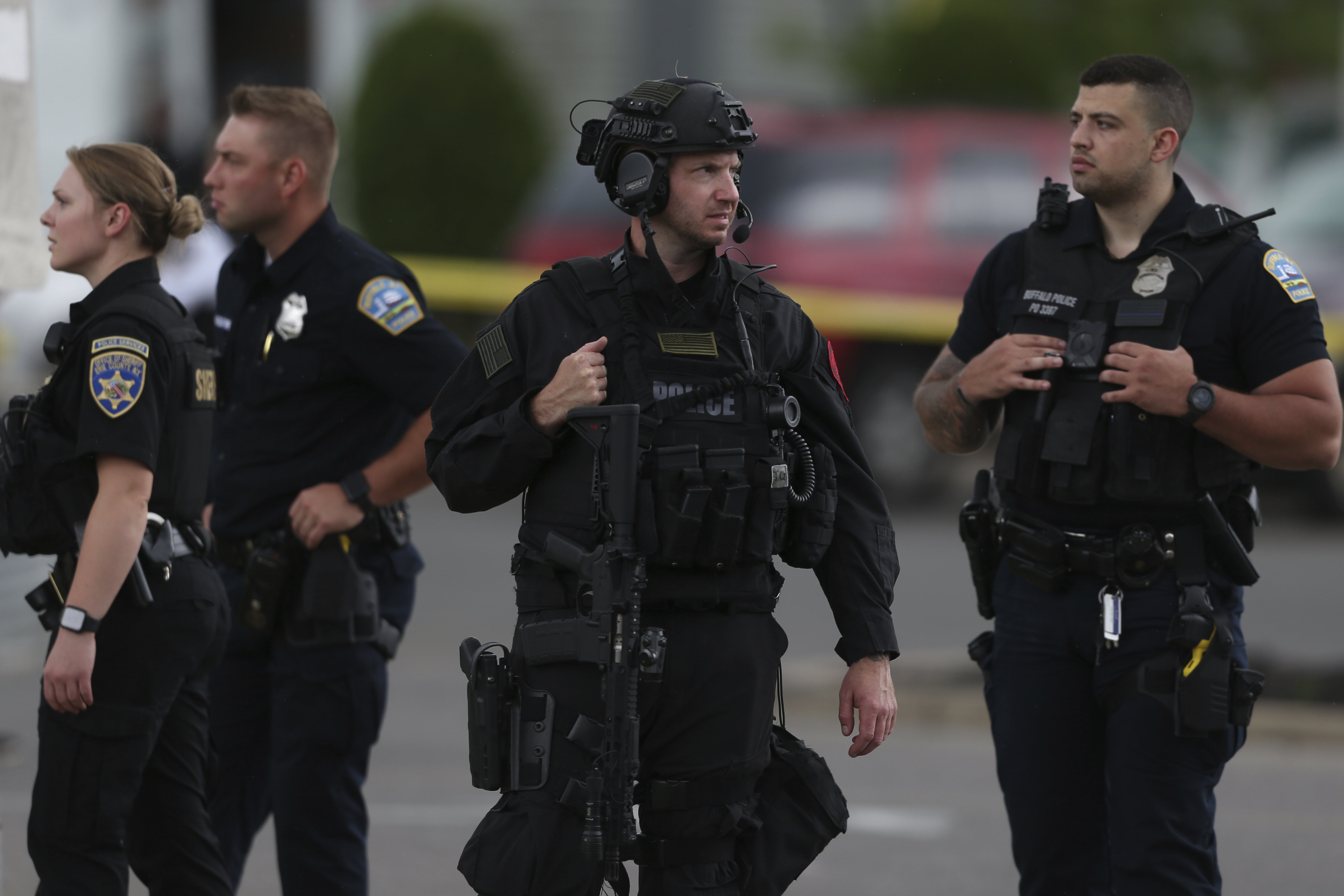 Police walk along the perimeter of the scene after a shooting at a supermarket on Saturday, May 14, 2022, in Buffalo