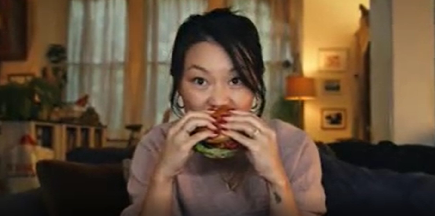 Woman takes bite out of plant burger in Tesco advert