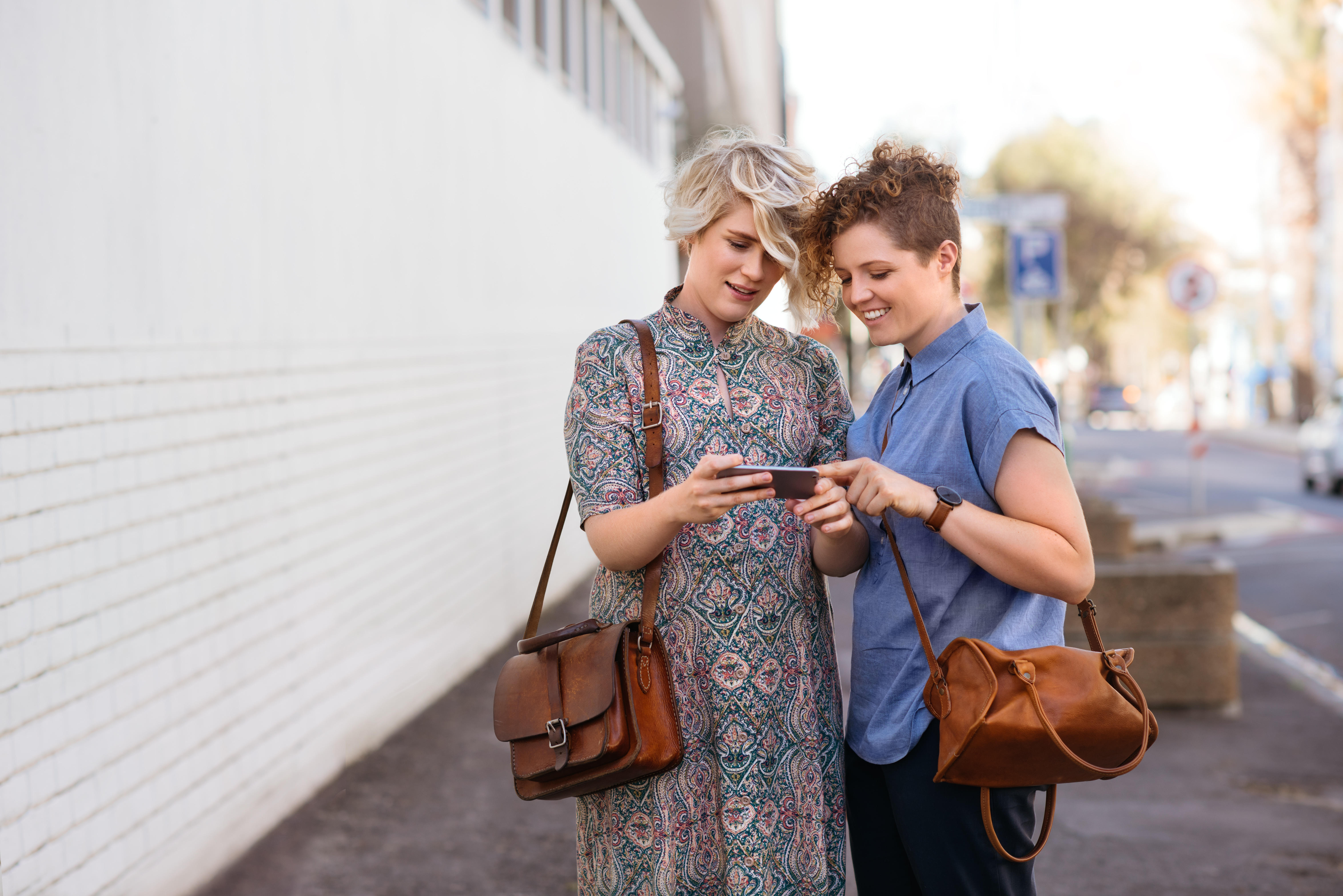 Lesbian couple outside, looking at a phone together