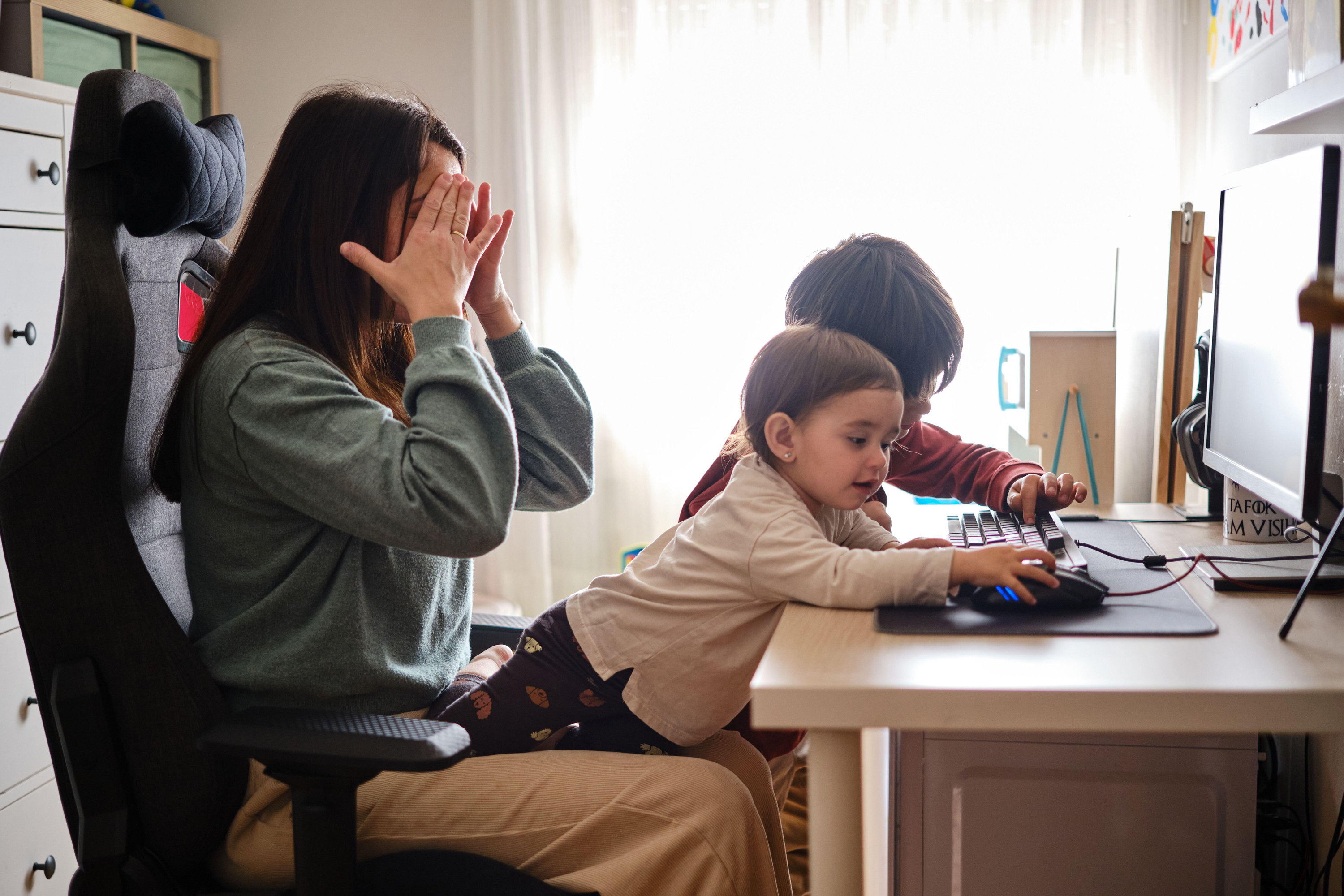 Stressed woman trying to work remotely from home with her kids