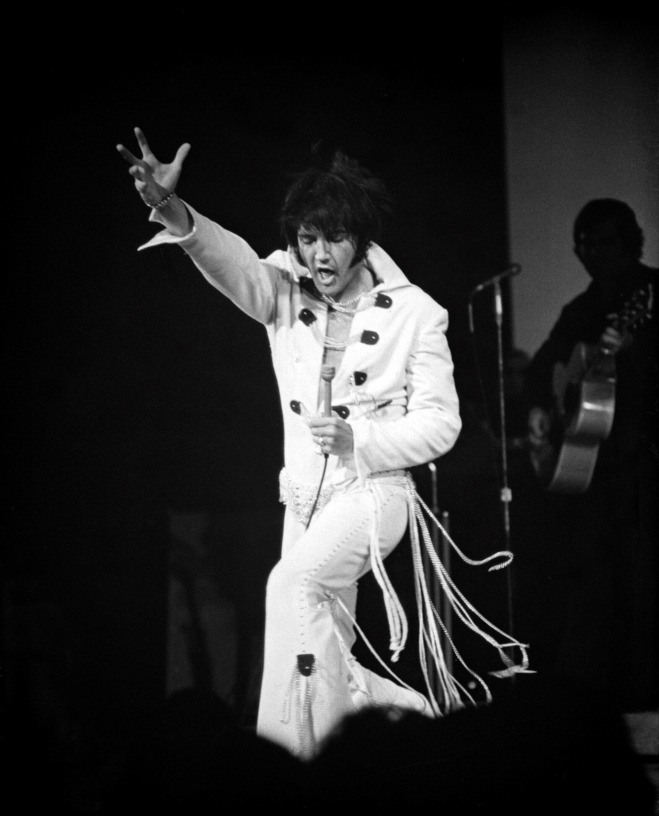 Elvis Presley performing on stage in his trademark white jumpsuit