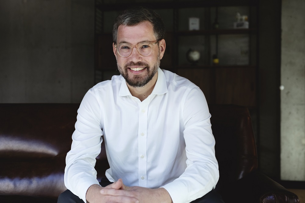 Man wearing a white shirt and glasses and smiling at the camera