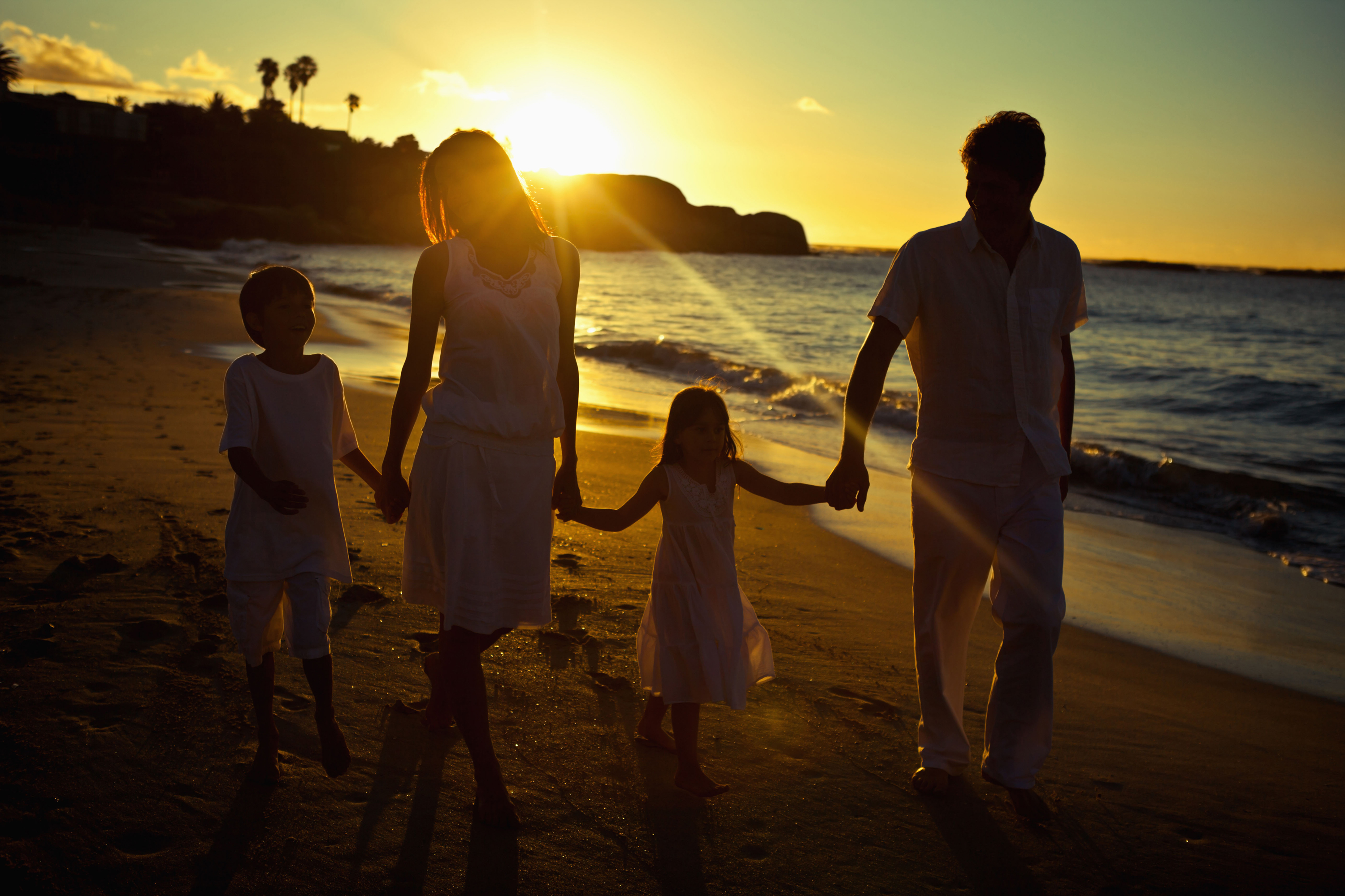 Family walking on the beach at sunset