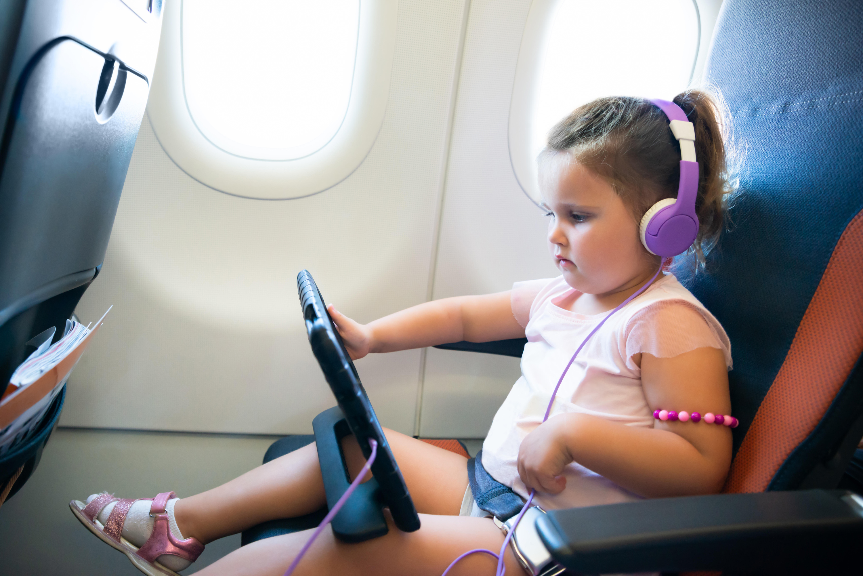 girl on plane playing on tablet