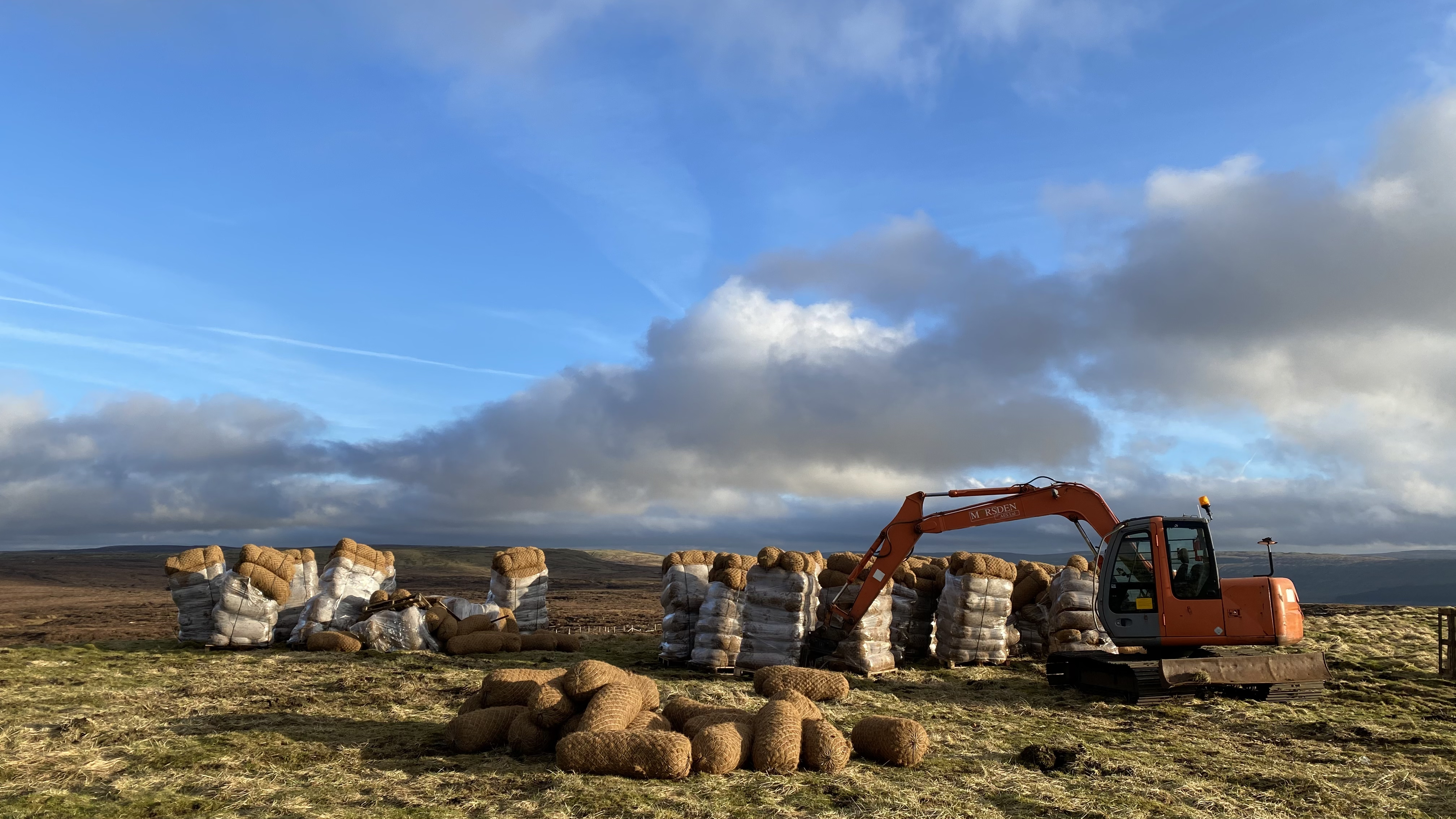 A digger with coir logs for blocking gullies to restore peat