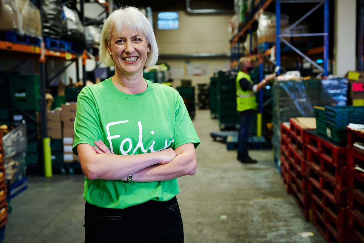 Woman wearing green t-shirt, with her arms crossed and smiling at the camera