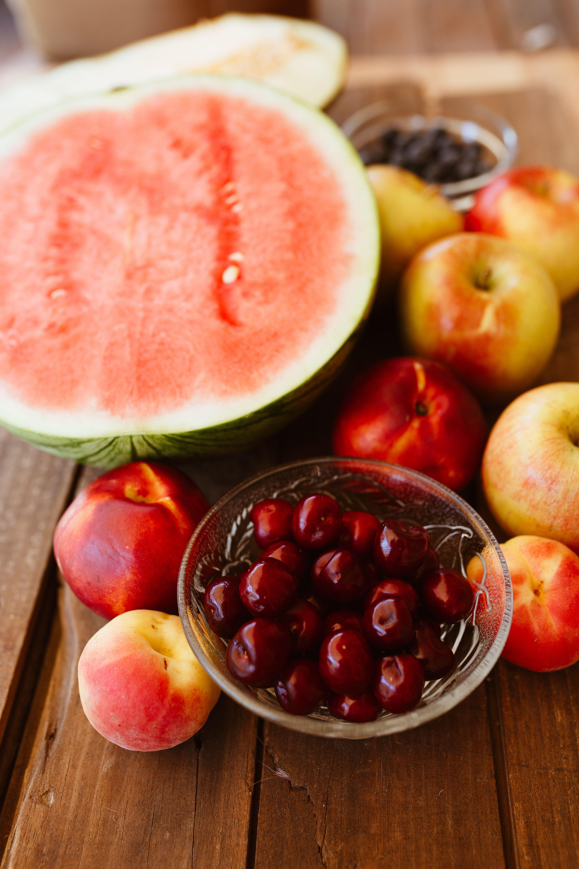 black cherries, melon, apples and peaches arranged on wooden table