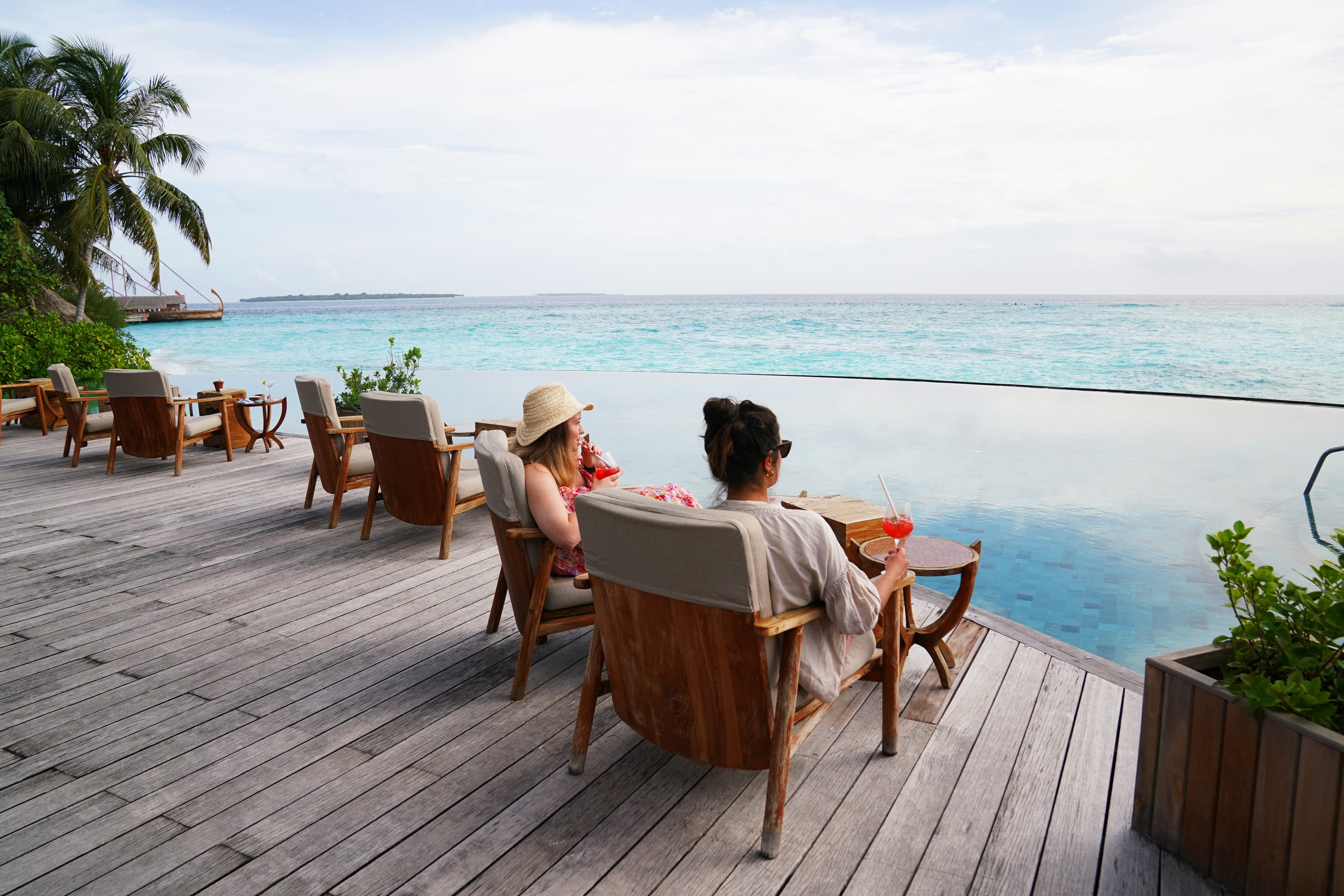 Two women sit and sip cocktails at the infinity pool of Milaidhoo’s Compass bar (Owen Humphries/PA) 