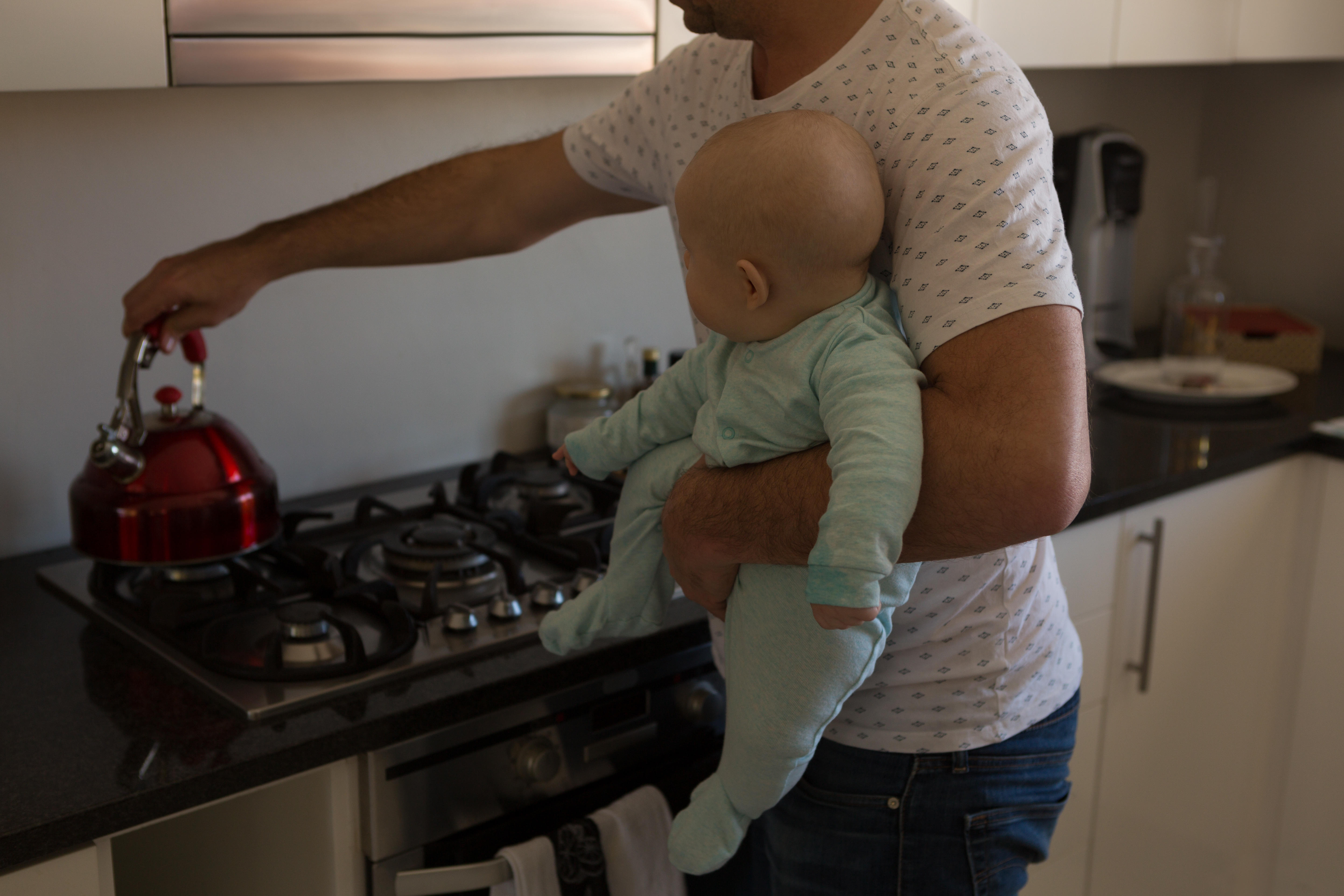 Father and baby boy preparing coffee in kitchen