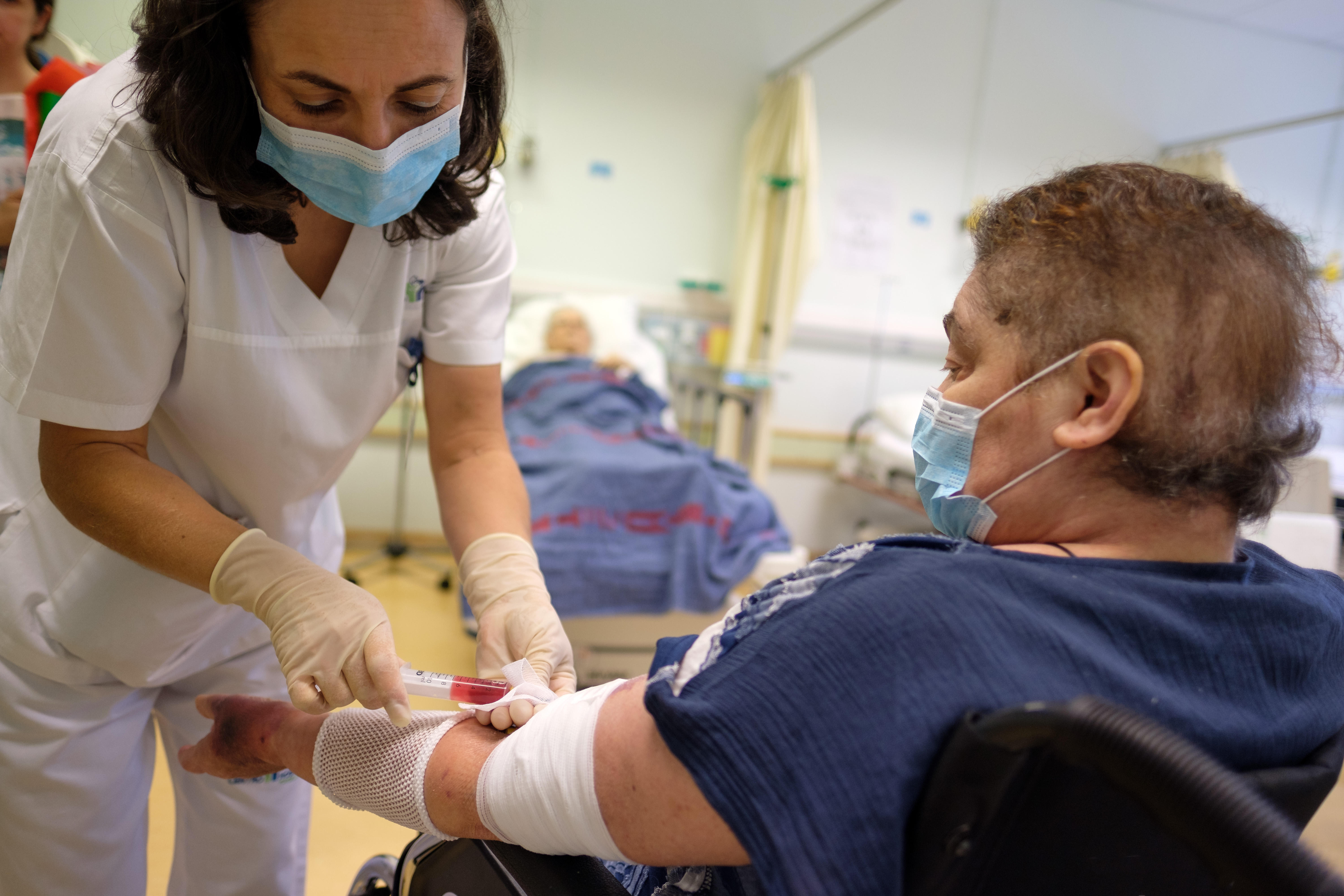 Nurse taking blood sample from elderly patient in a hospital ward