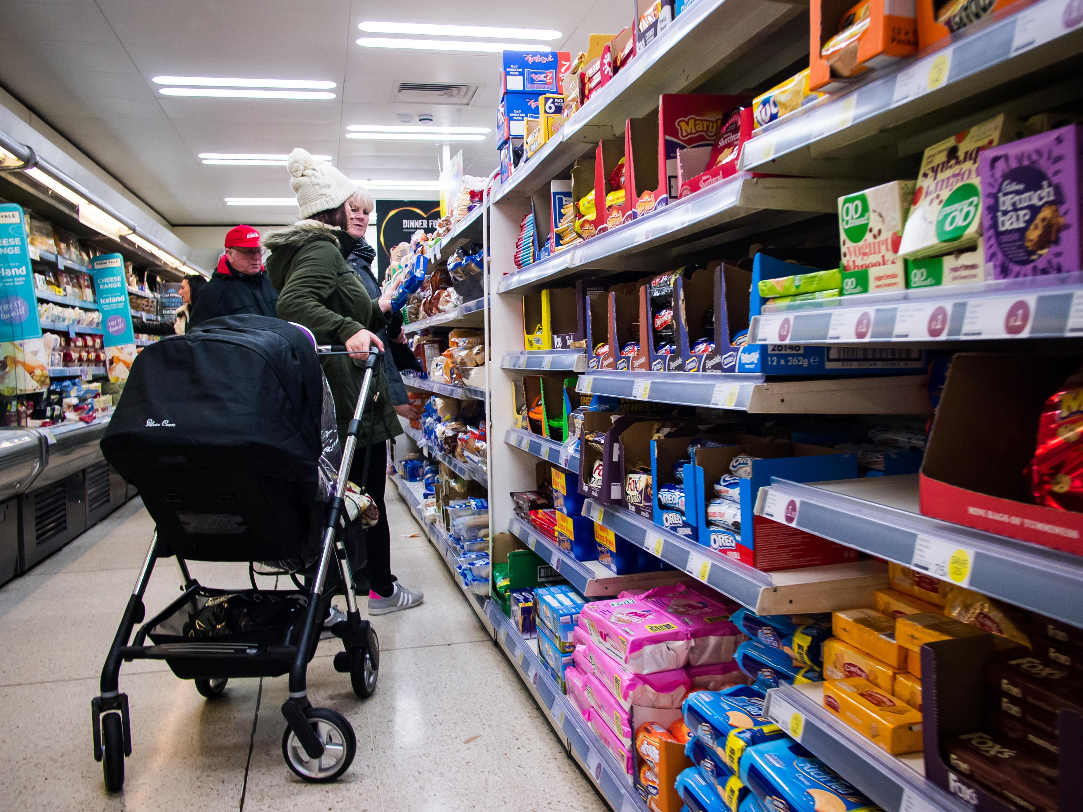 A mother shopping at a supermarket with a pram