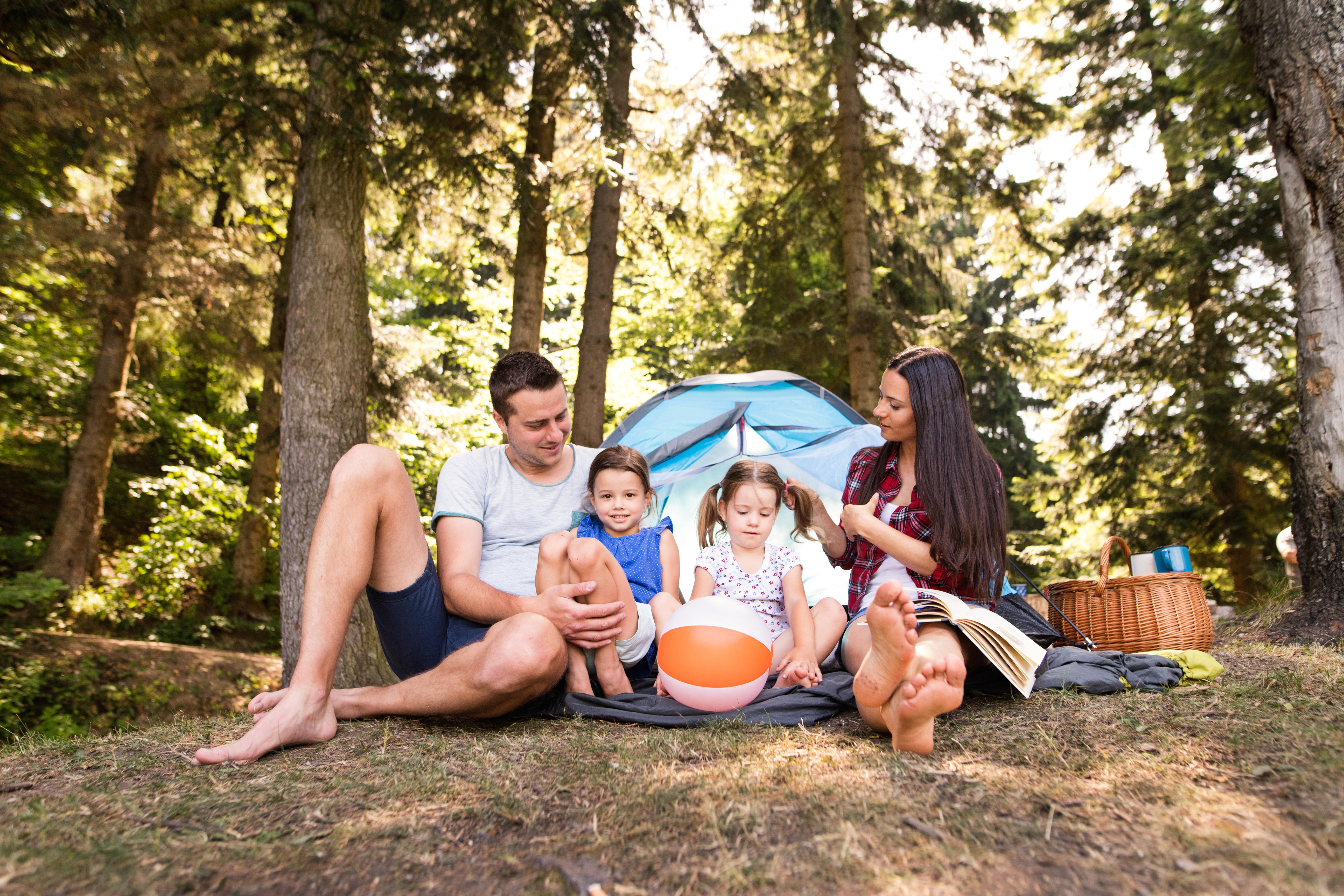 Family sitting outside a tent enjoying summer