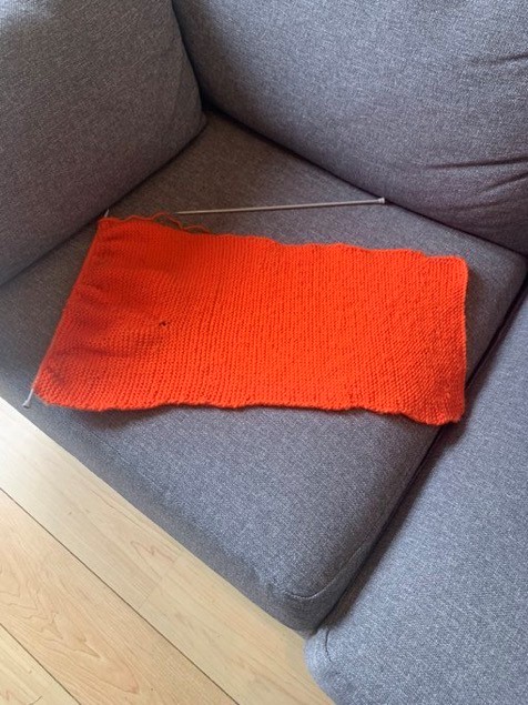 Orange knit on a grey sofa
