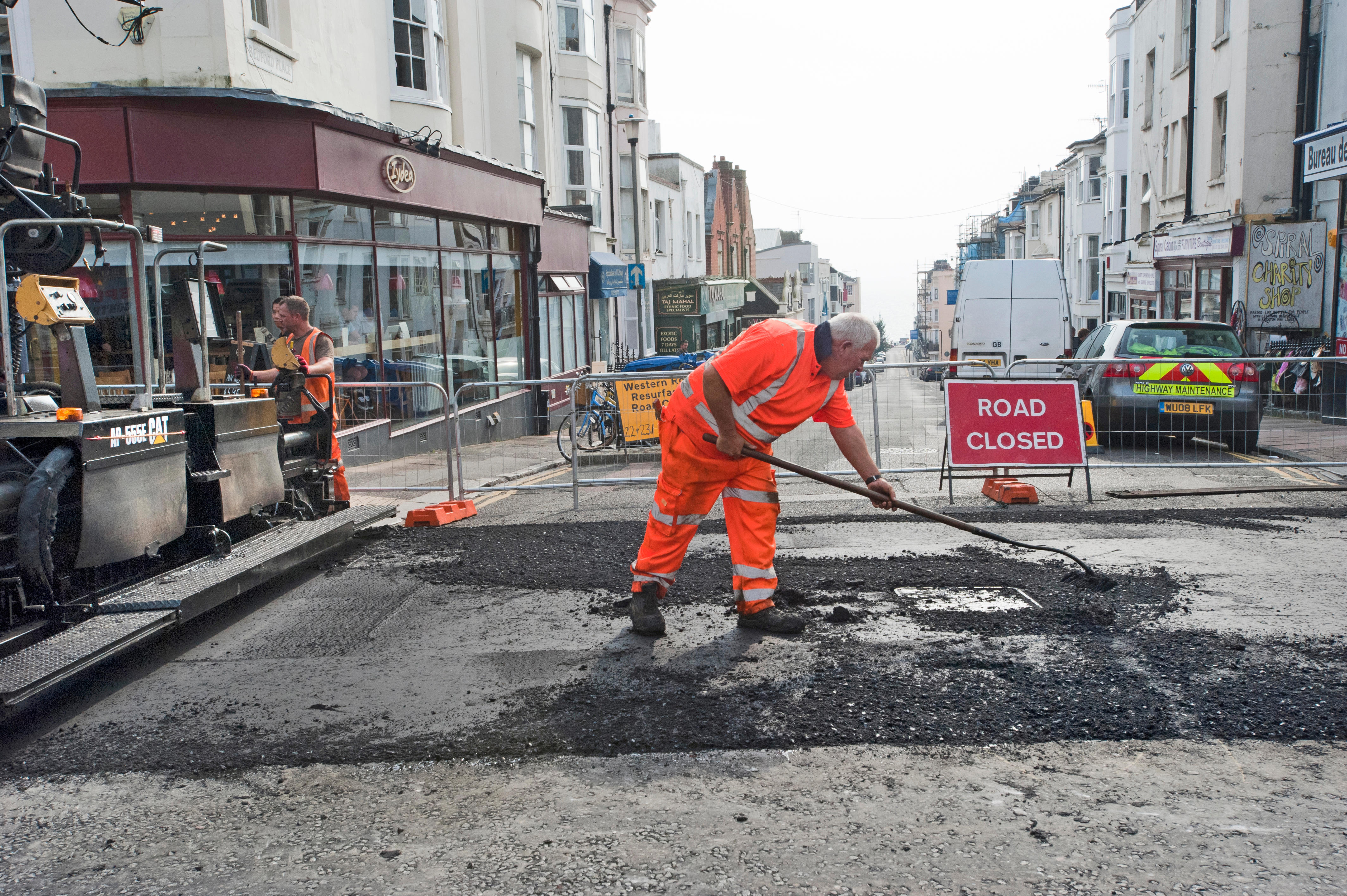 A highway maintenance worker mends a pothole in a road in Brighton