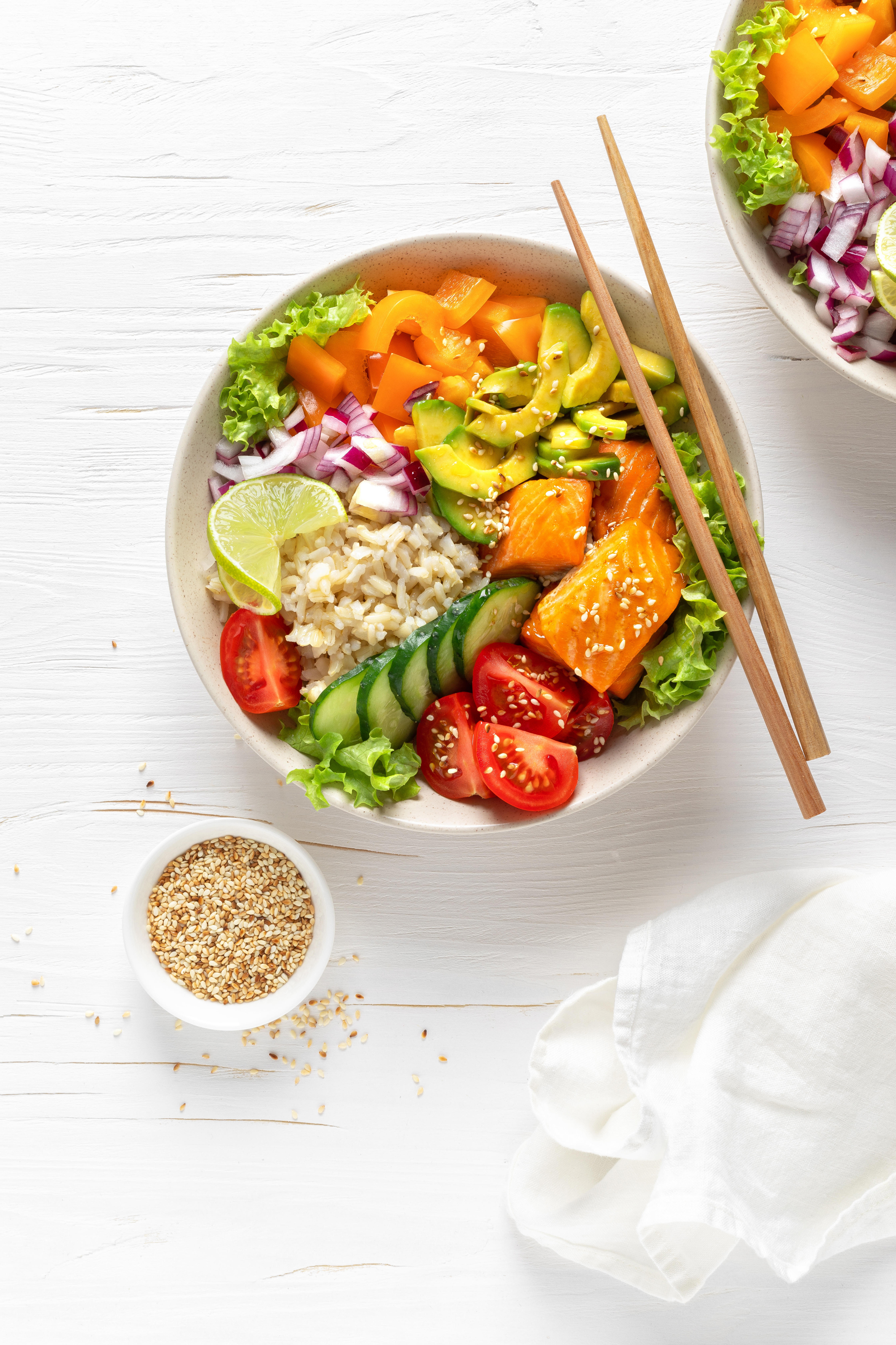 Buddha bowl with grilled salmon fish, fresh cucumber, tomato, onion, sweet pepper, avocado, lettuce salad and rice