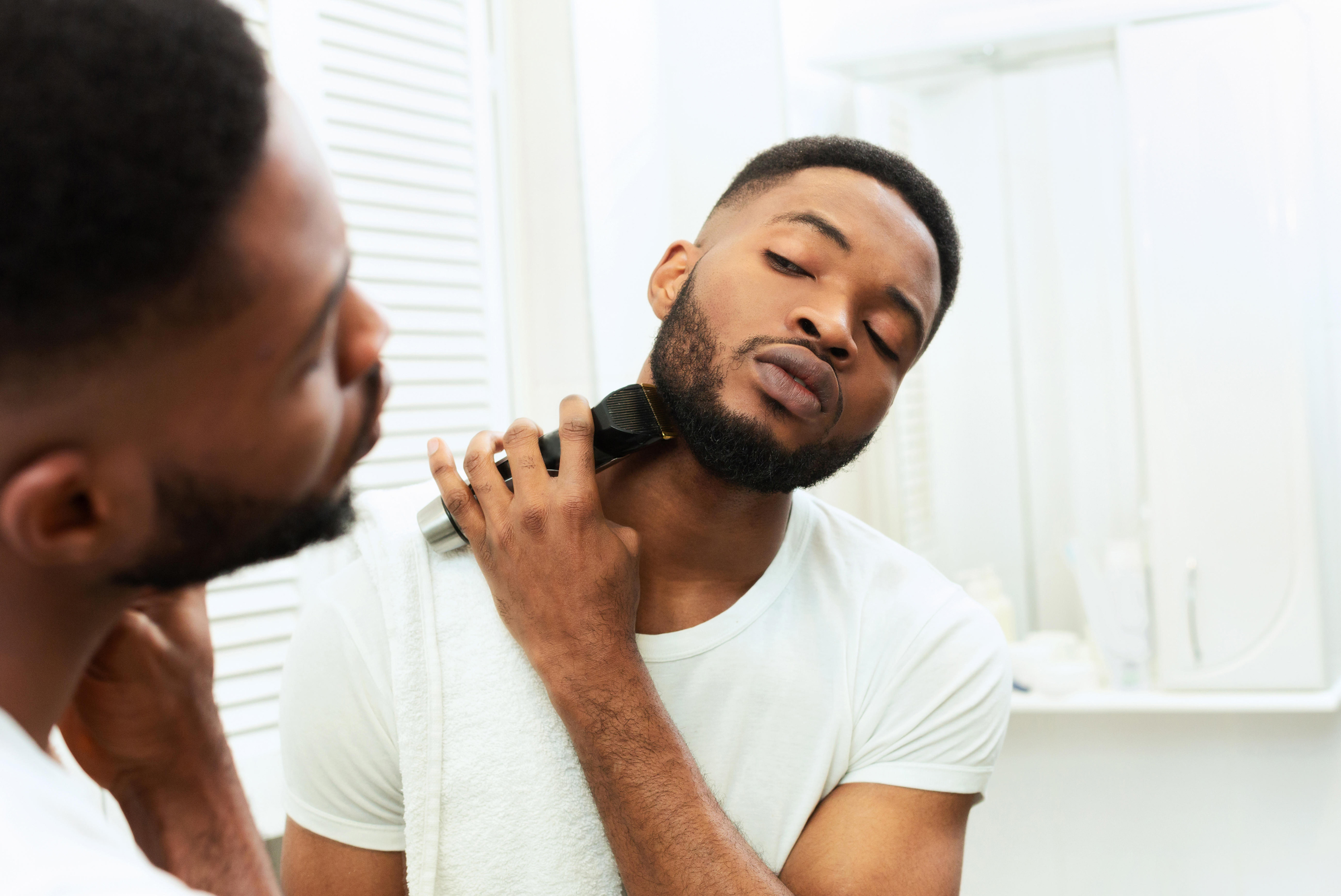 man trimming beard in mirror