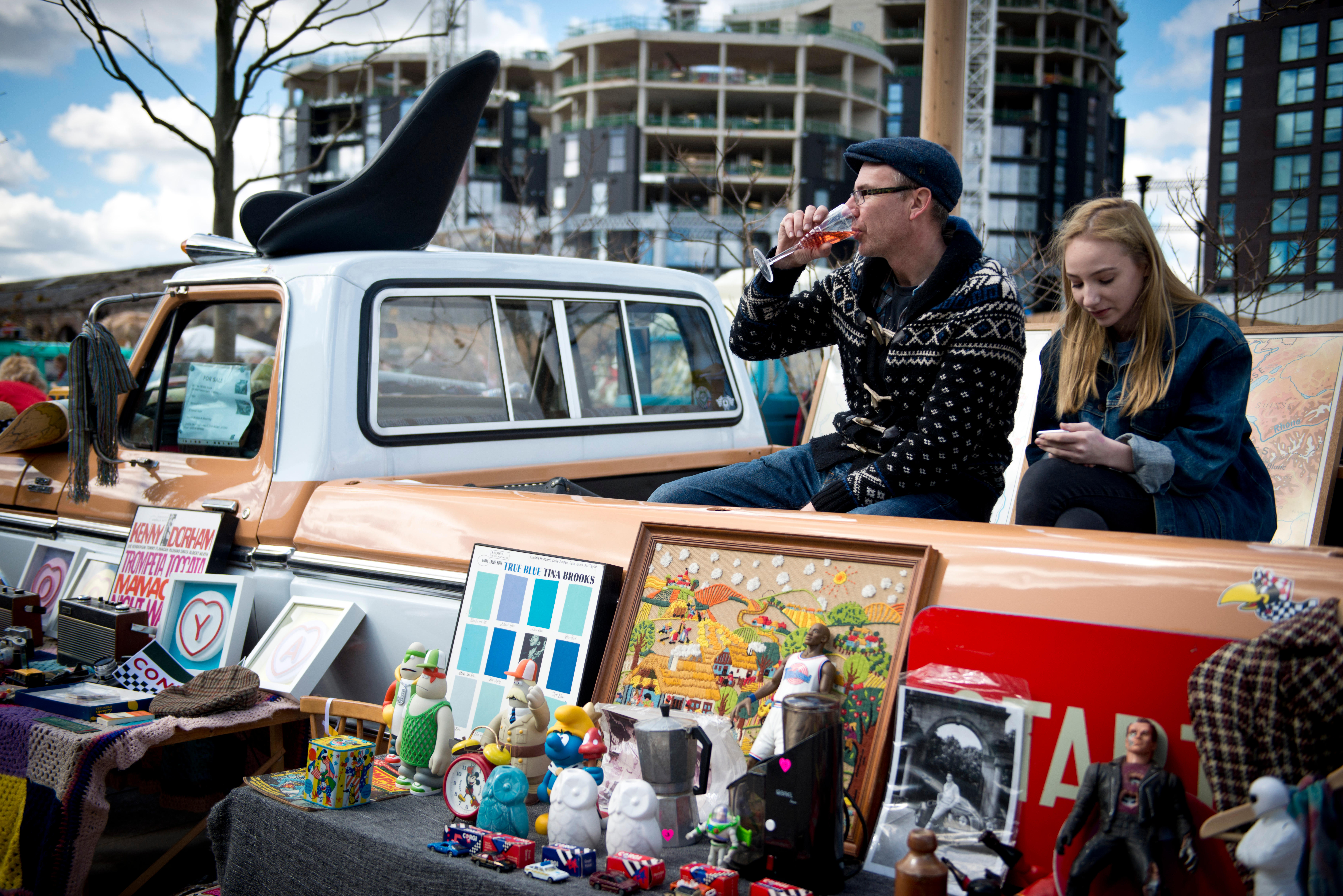 A young couple sitting behind a stall at a car boot sale