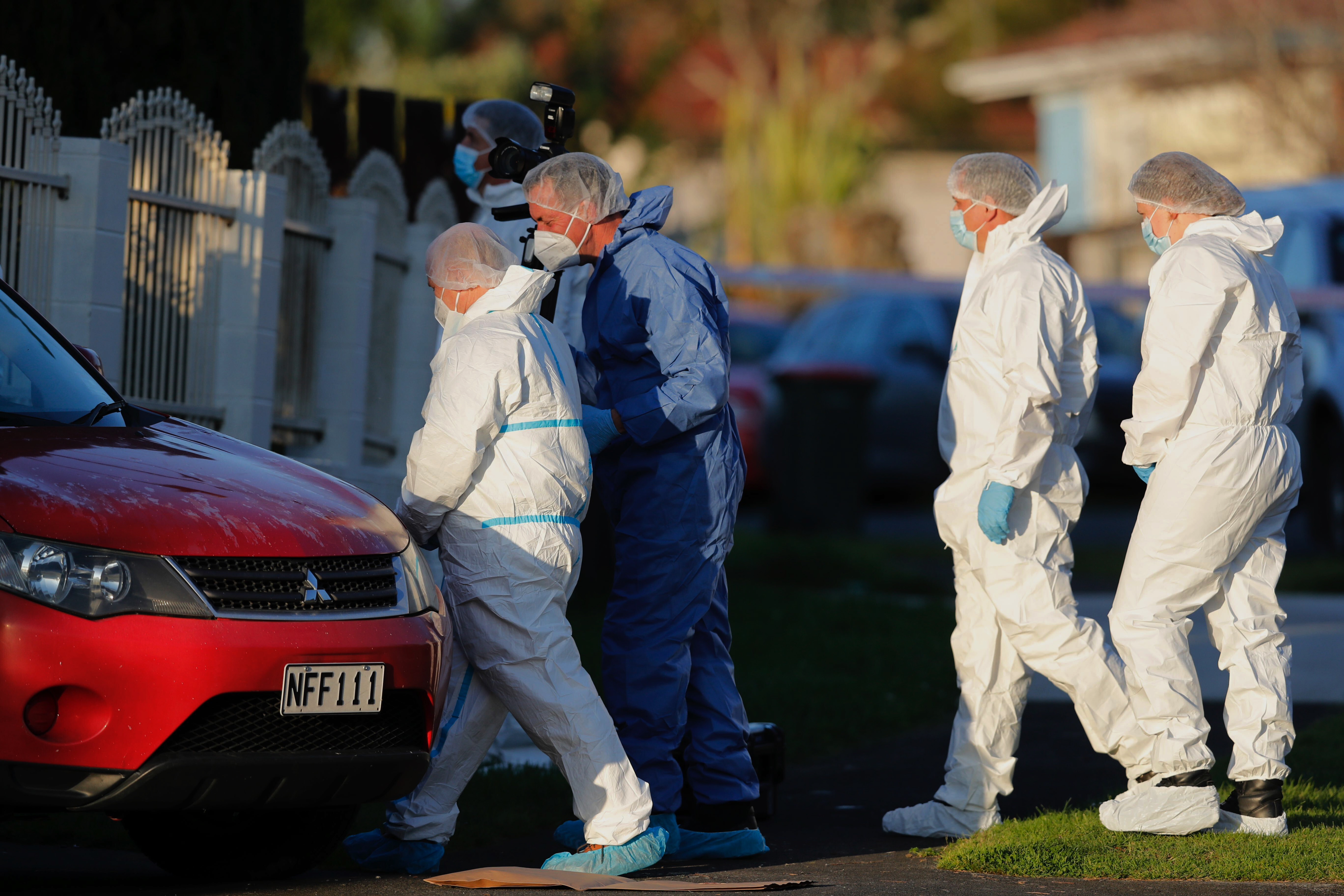 New Zealand police investigators work at a scene in Auckland after bodies were discovered in suitcases 