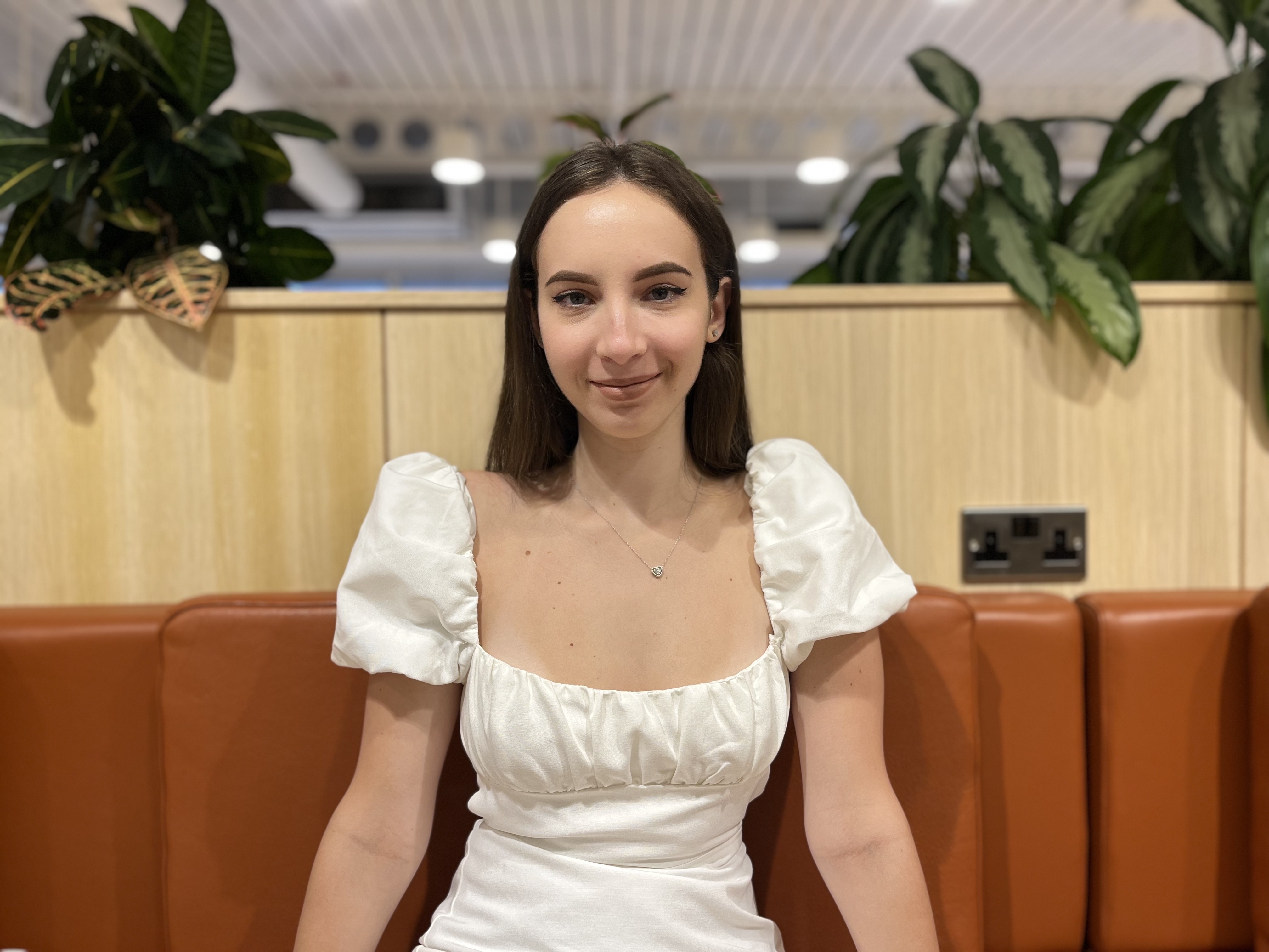 Girl wearing a white dress and sitting on a couch