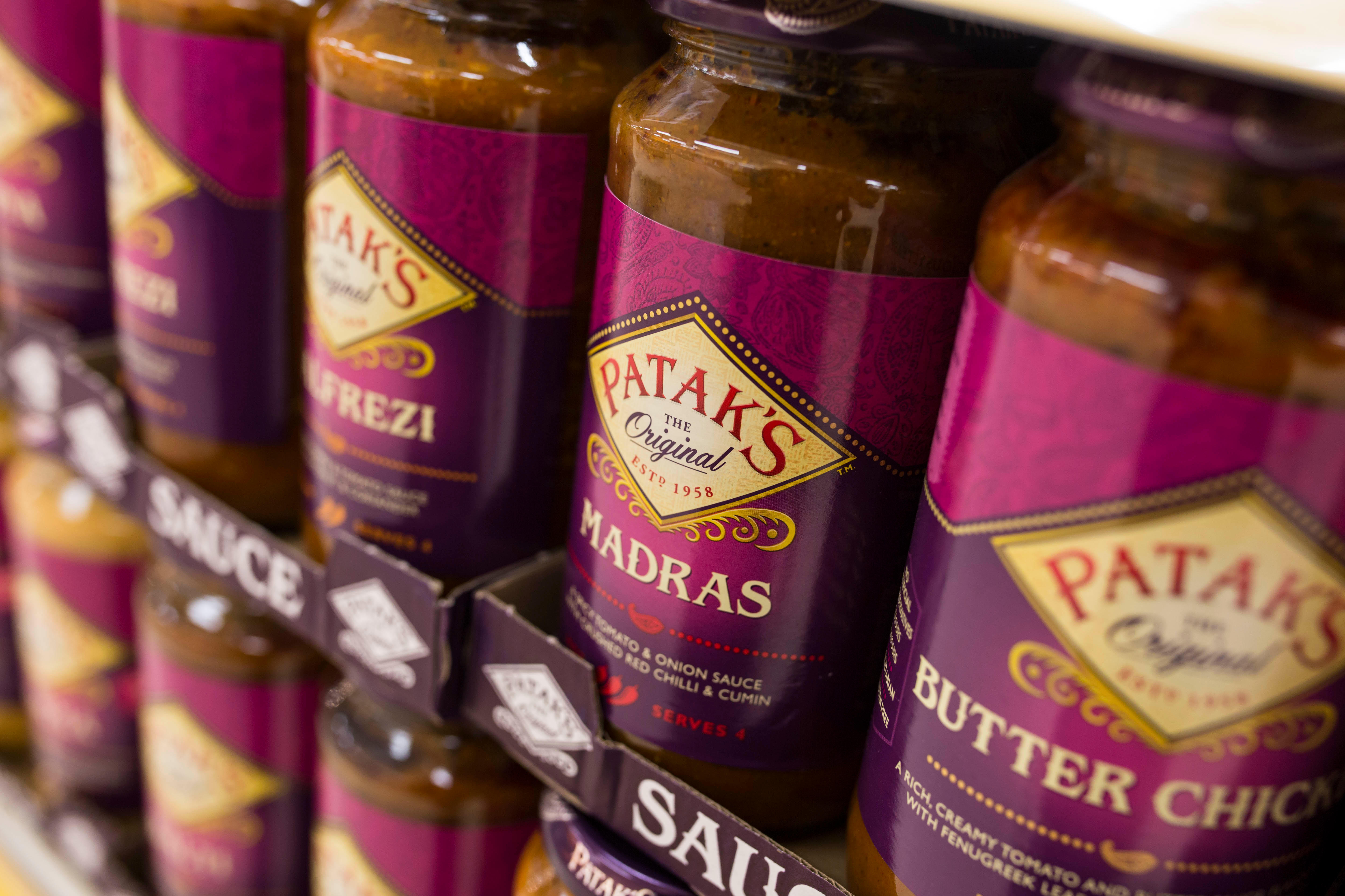 Jars of Patak's curry sauce on a  shelf in a supermarket