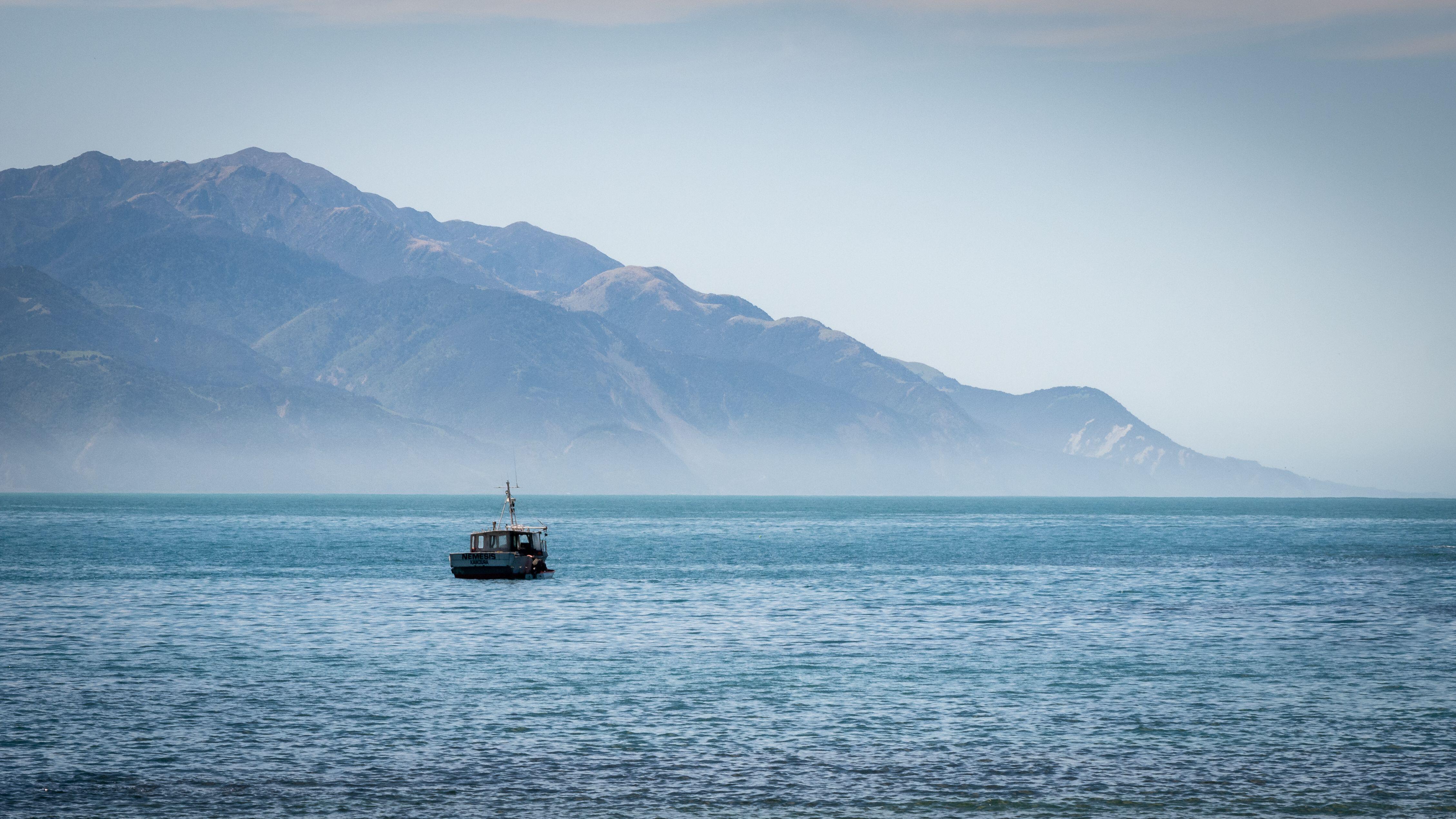 Boat on the ocean with mountain backdrop. Shot at Kaikoura peninsula, New Zealand