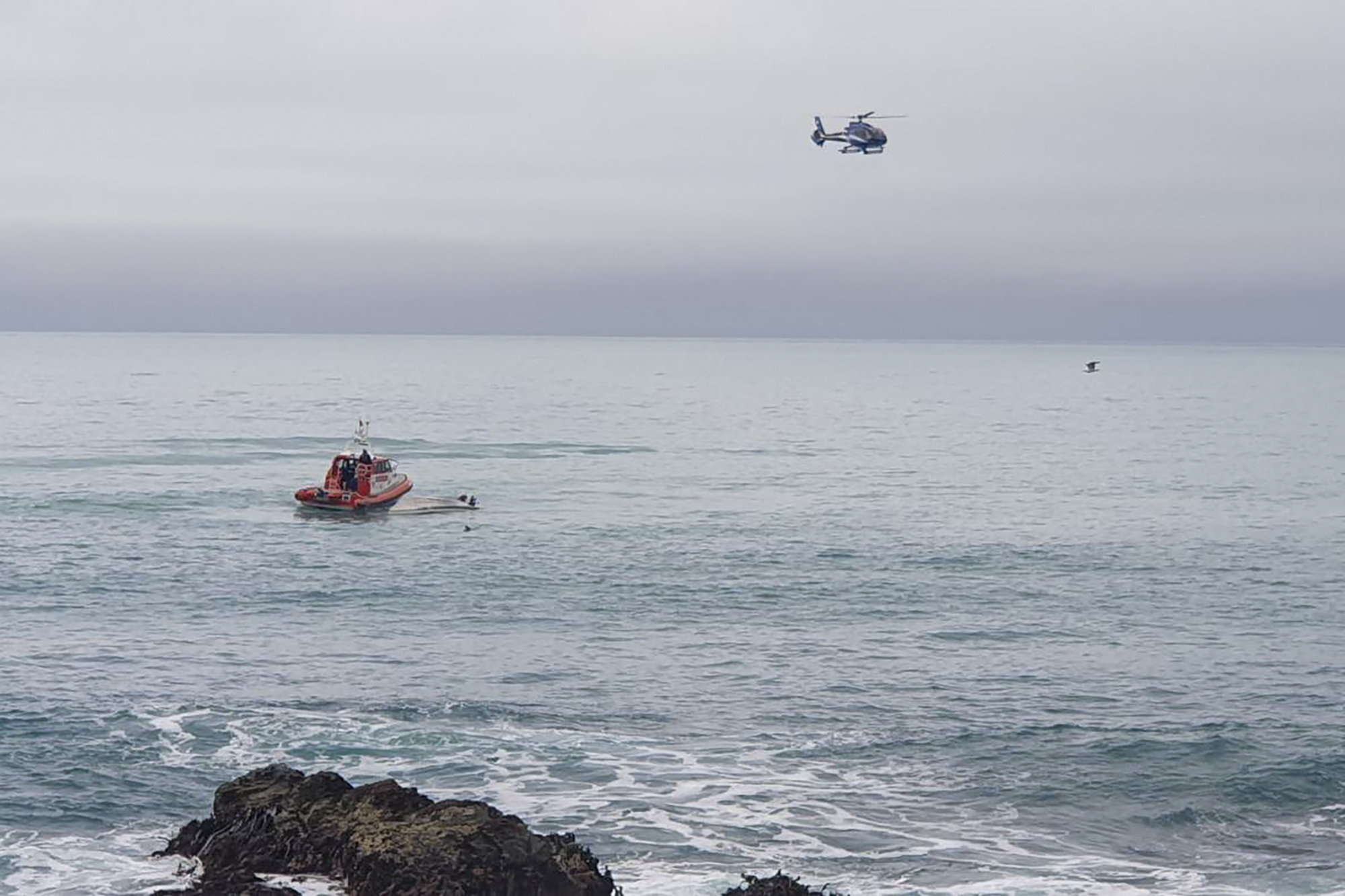 A helicopter and a rescue boat search for survivors off the coast of Kaikoura, New Zealand, Saturday