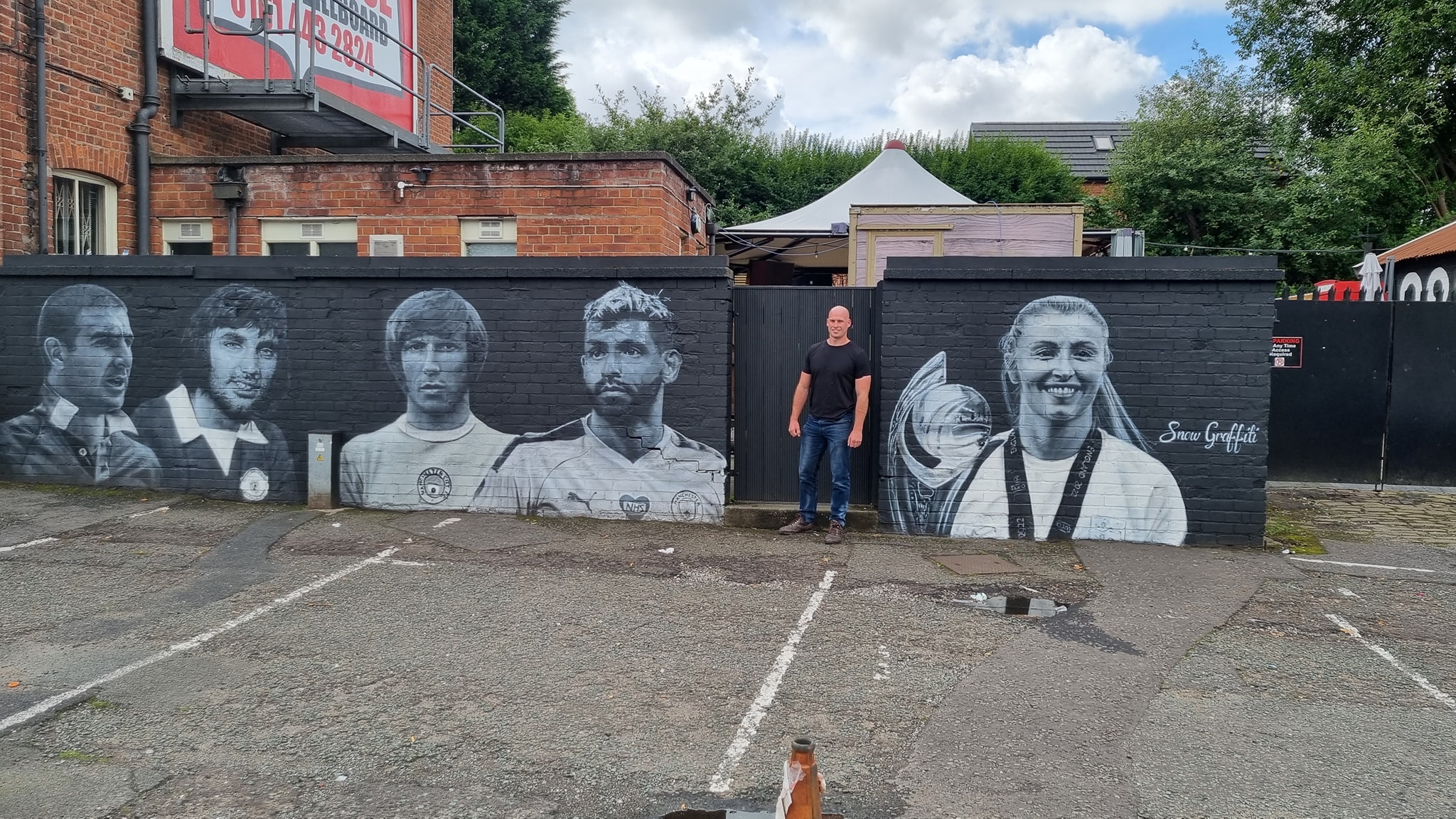 Scott Wilcock with his football icons mural for a pub in Prestwich, Manchester. 