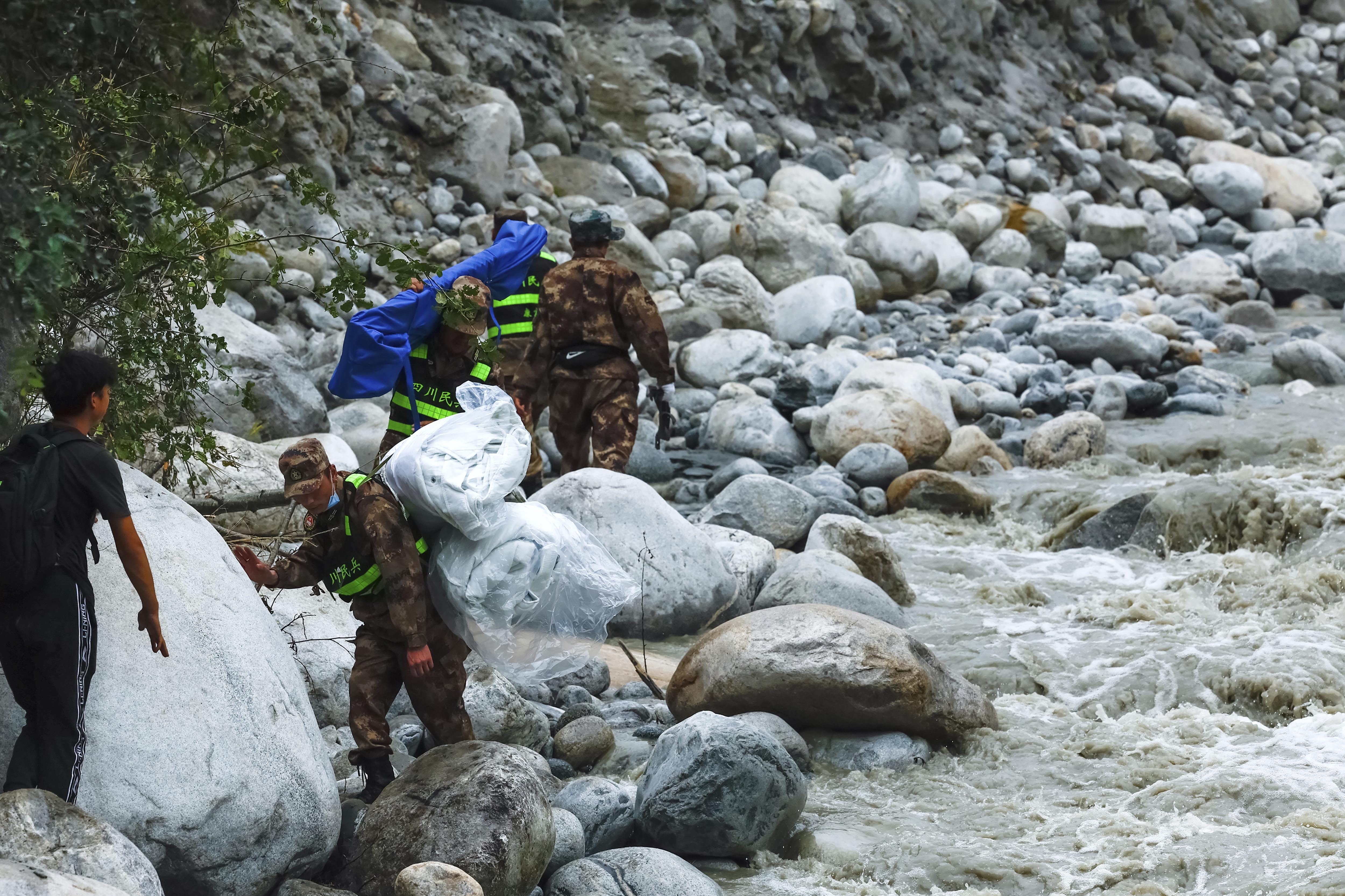 Rescuers deliver supplies via an uphill path in the aftermath of an earthquake along the Moxi River near Moxi Town of Luding County, southwest China's Sichuan Province