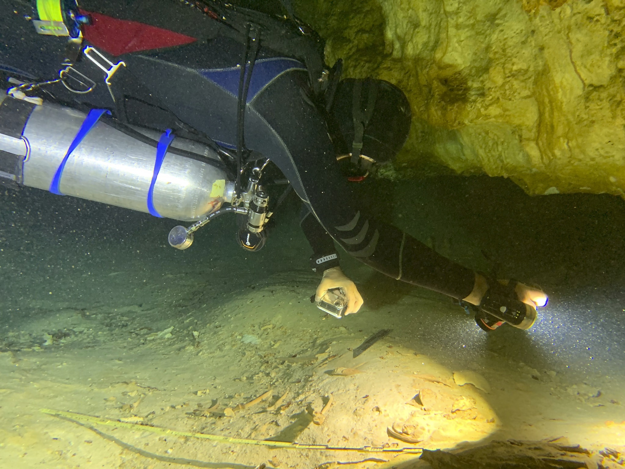 Aquatic archaeologist Octavio del Rio films a prehistoric human skeleton partly covered by sediment in an underwater cave in Tulum, Mexico