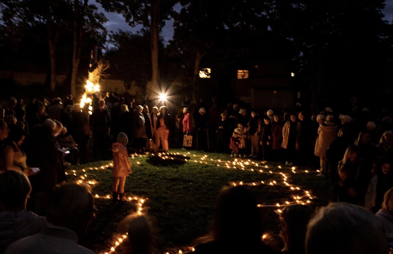Candles on grass with people standing next to it