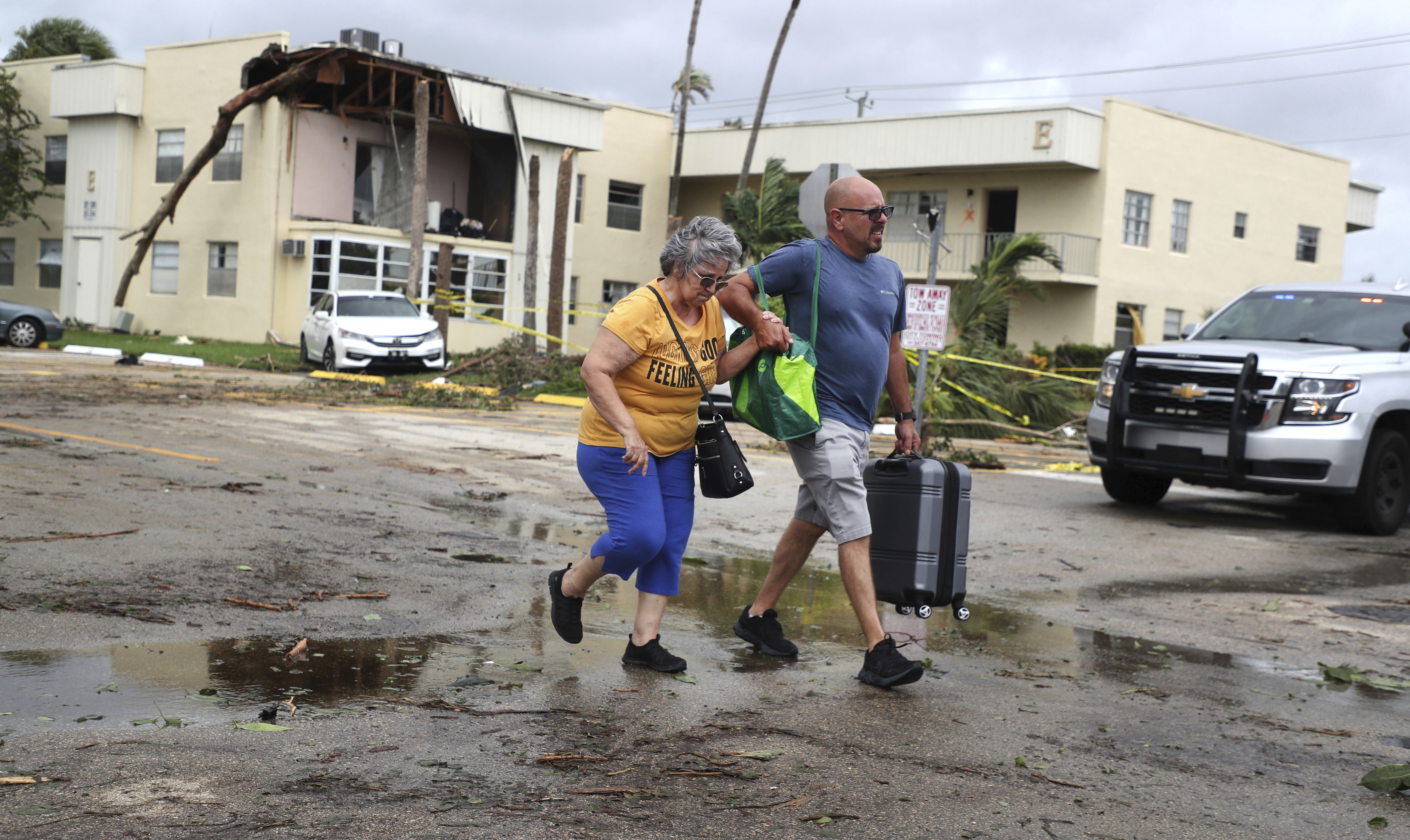 King Point resident Maria Esturilho is escorted by her son Tony Esturilho as they leave behind the damage from an apparent overnight tornado spawned from Hurricane Ian at Kings Point 55+ community in Delray Beach, Florida