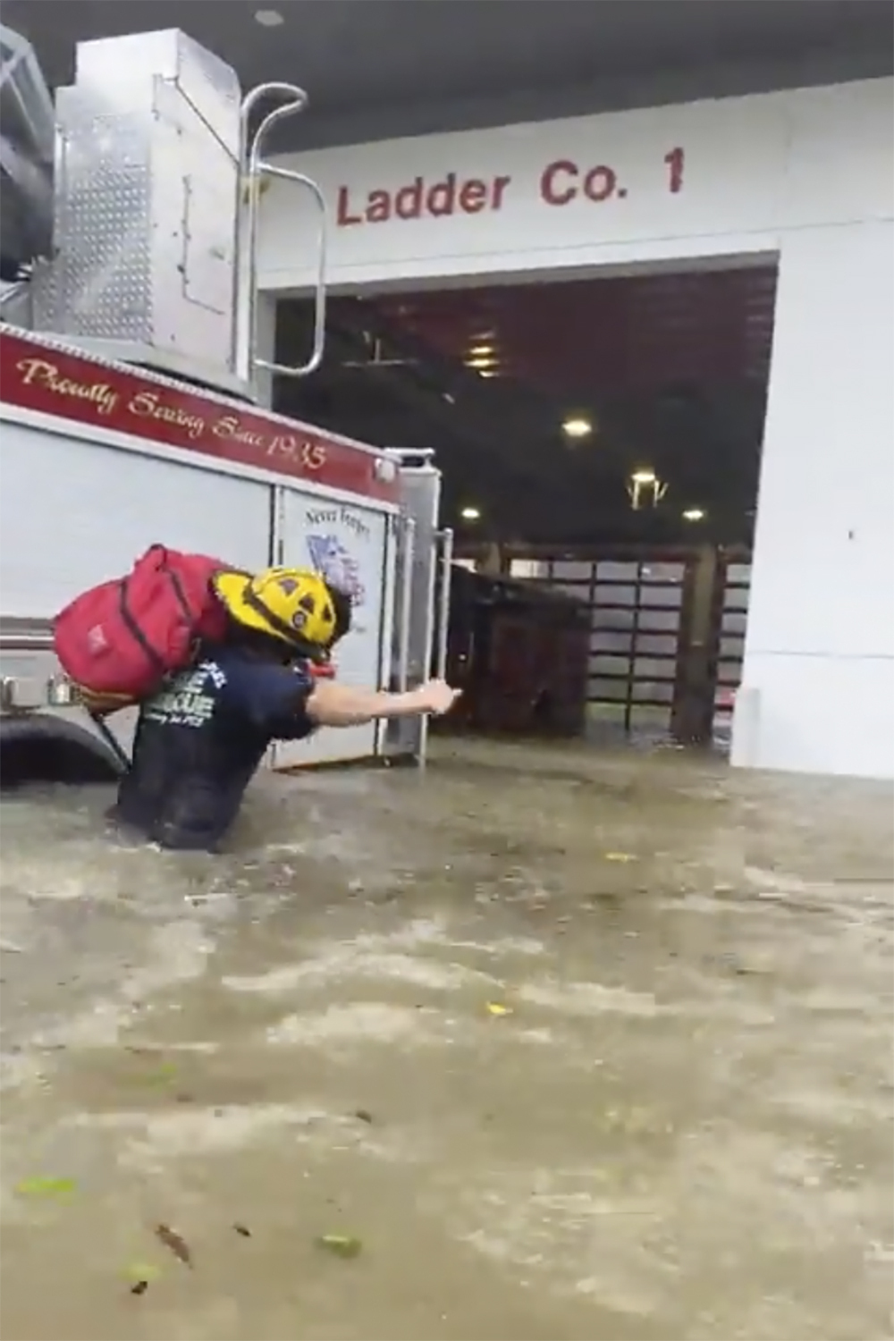 A firefighter carrying gear in water in Naples, Florida
