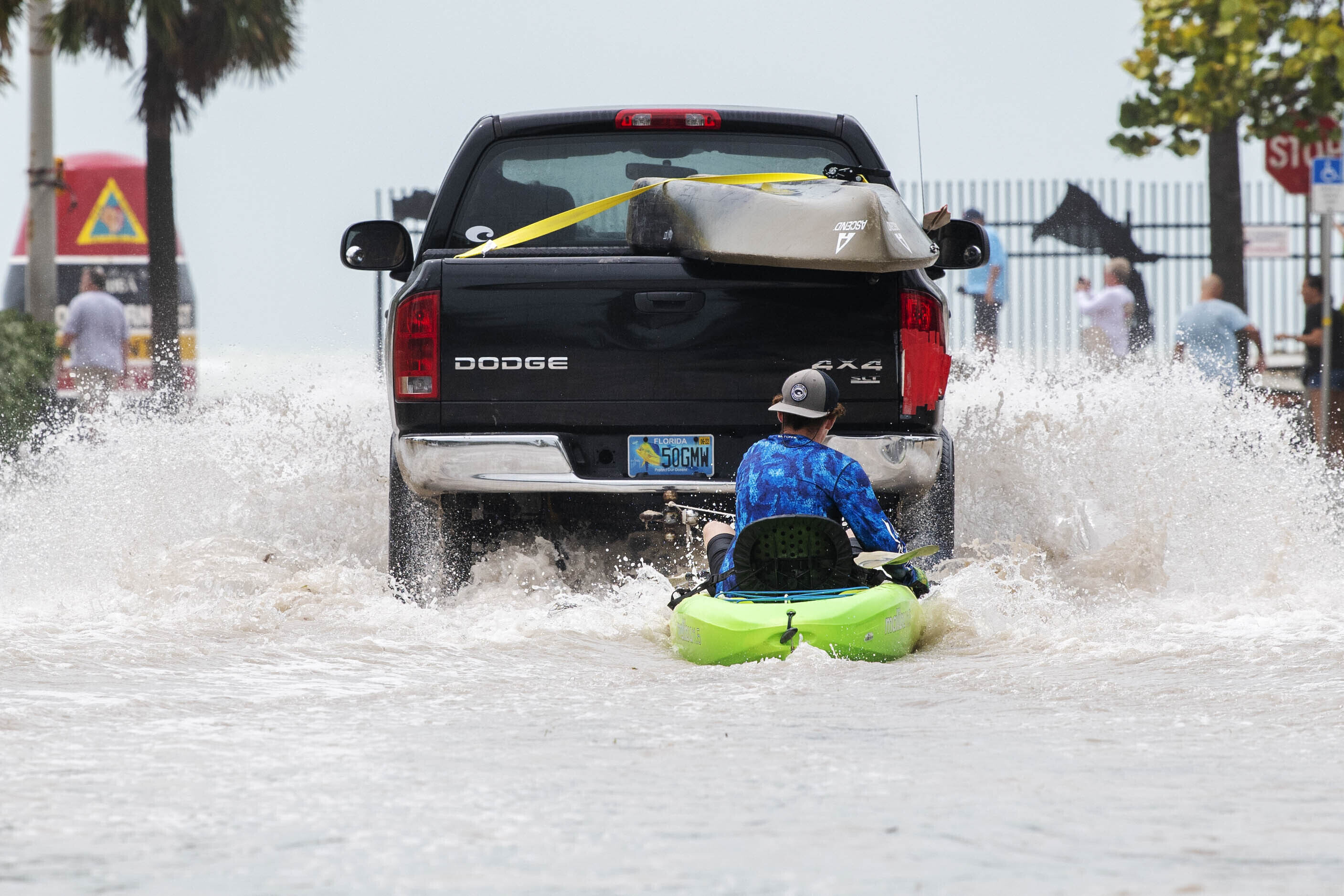 A truck pulls a man on a kayak on a low-lying road after flooding in Key West, Florida