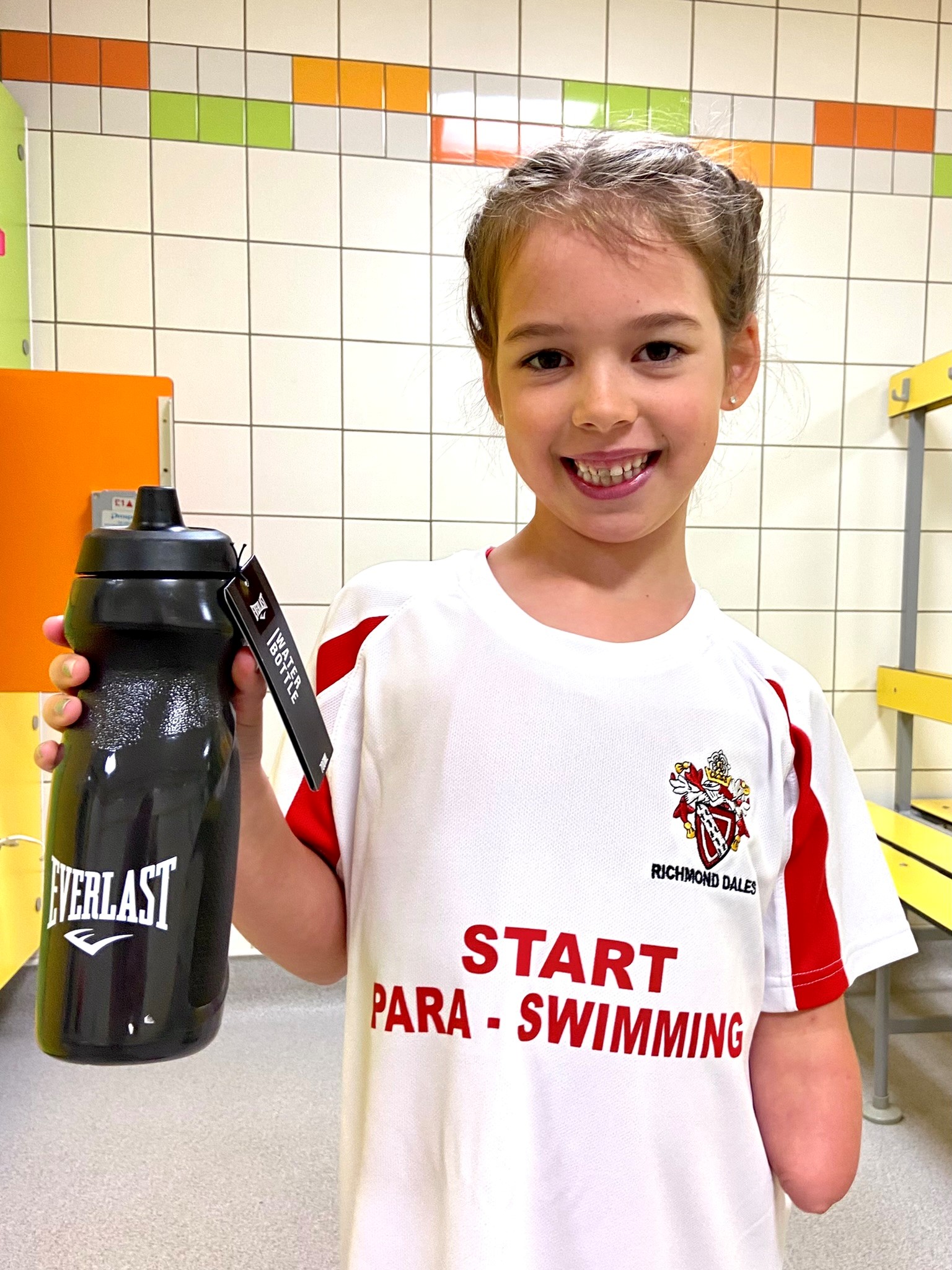 Little girl holding a water bottle and looking at the camera