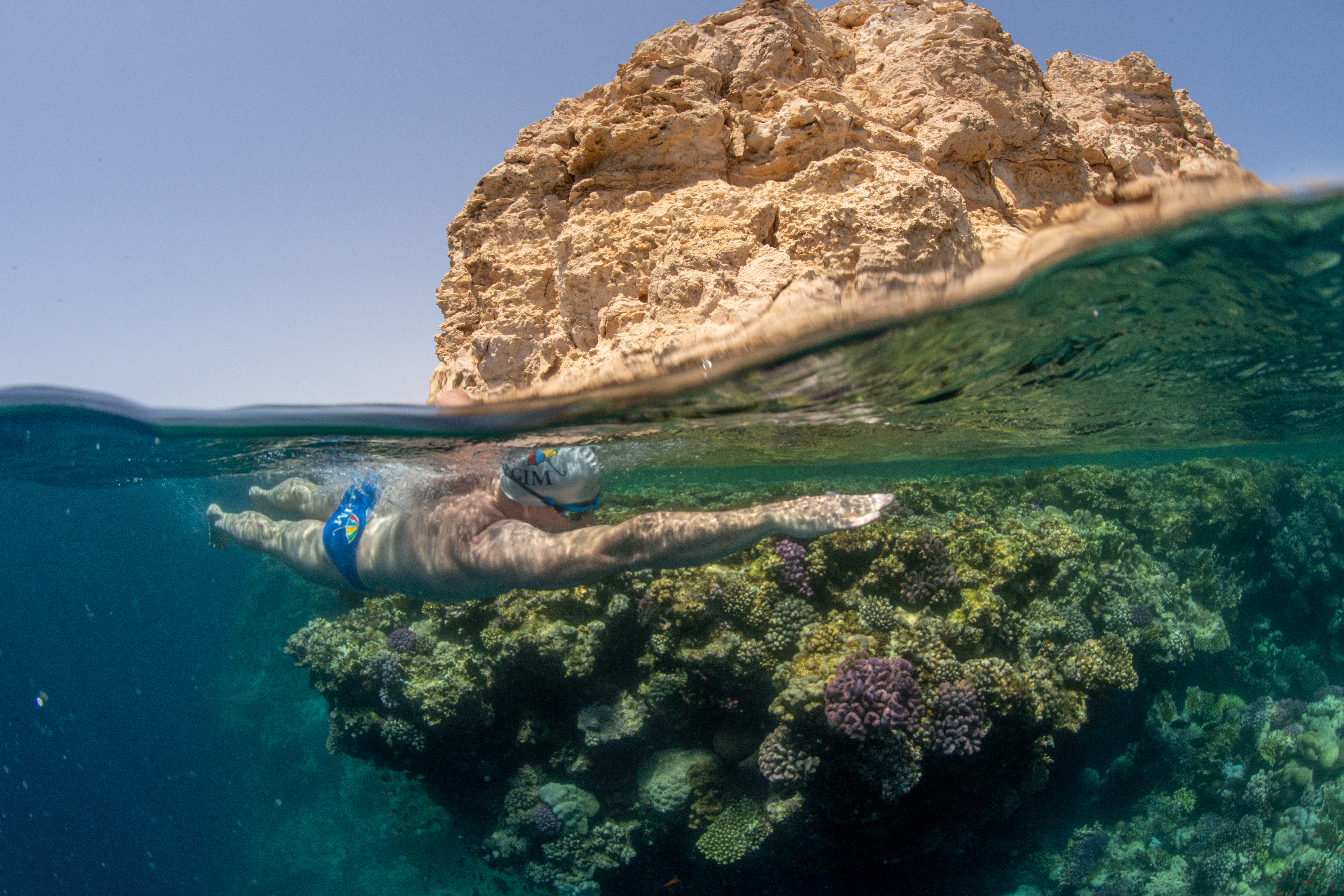 View of Lewis Pugh swimming past underwater coral and rocks above the sea