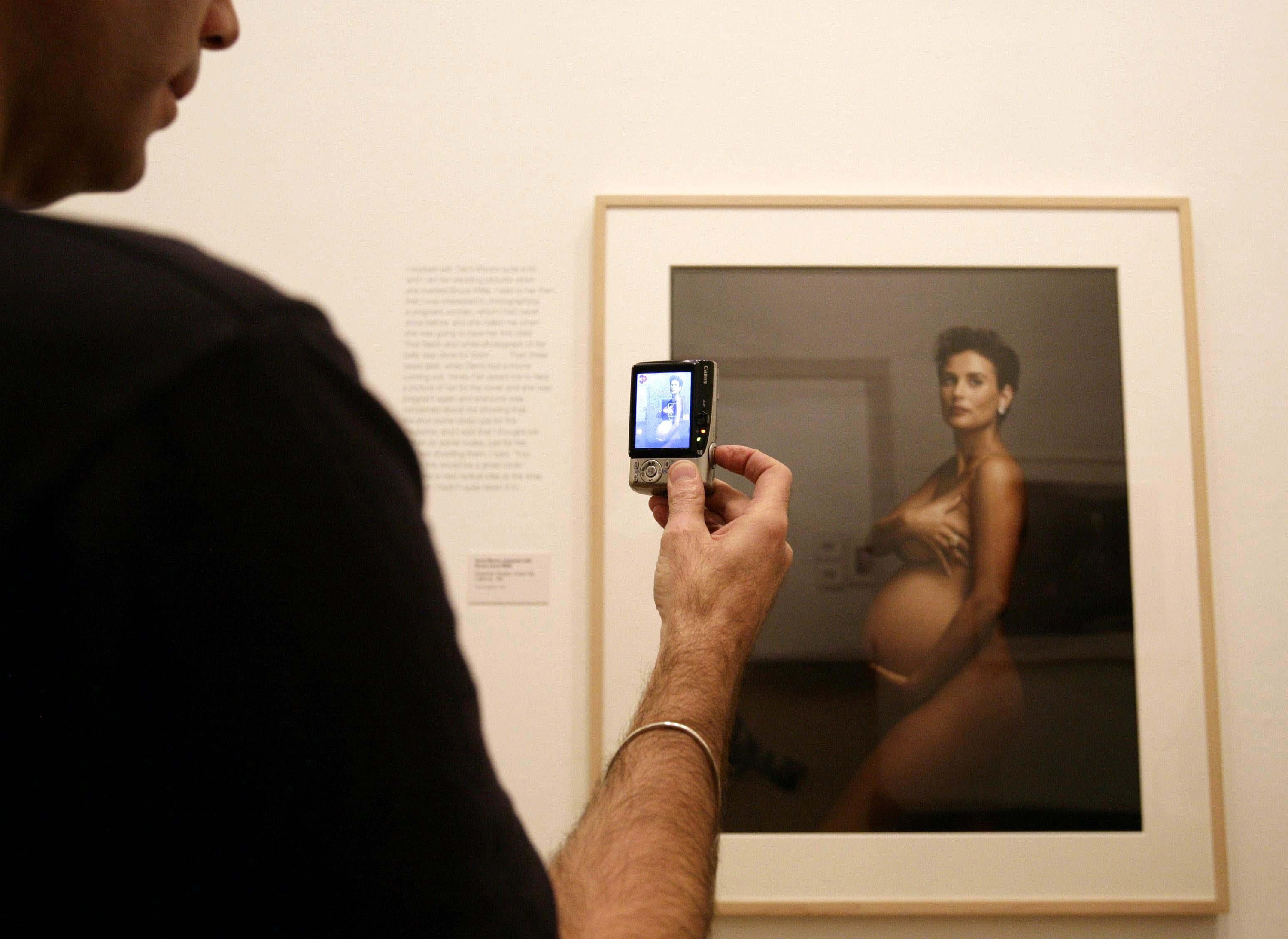 A visitor photographs Annie Leibovitz's portrait of a pregnant Demi Moore, during the launch of her exhibition Annie Leibovitz: A Photographer's Life 1990-2005