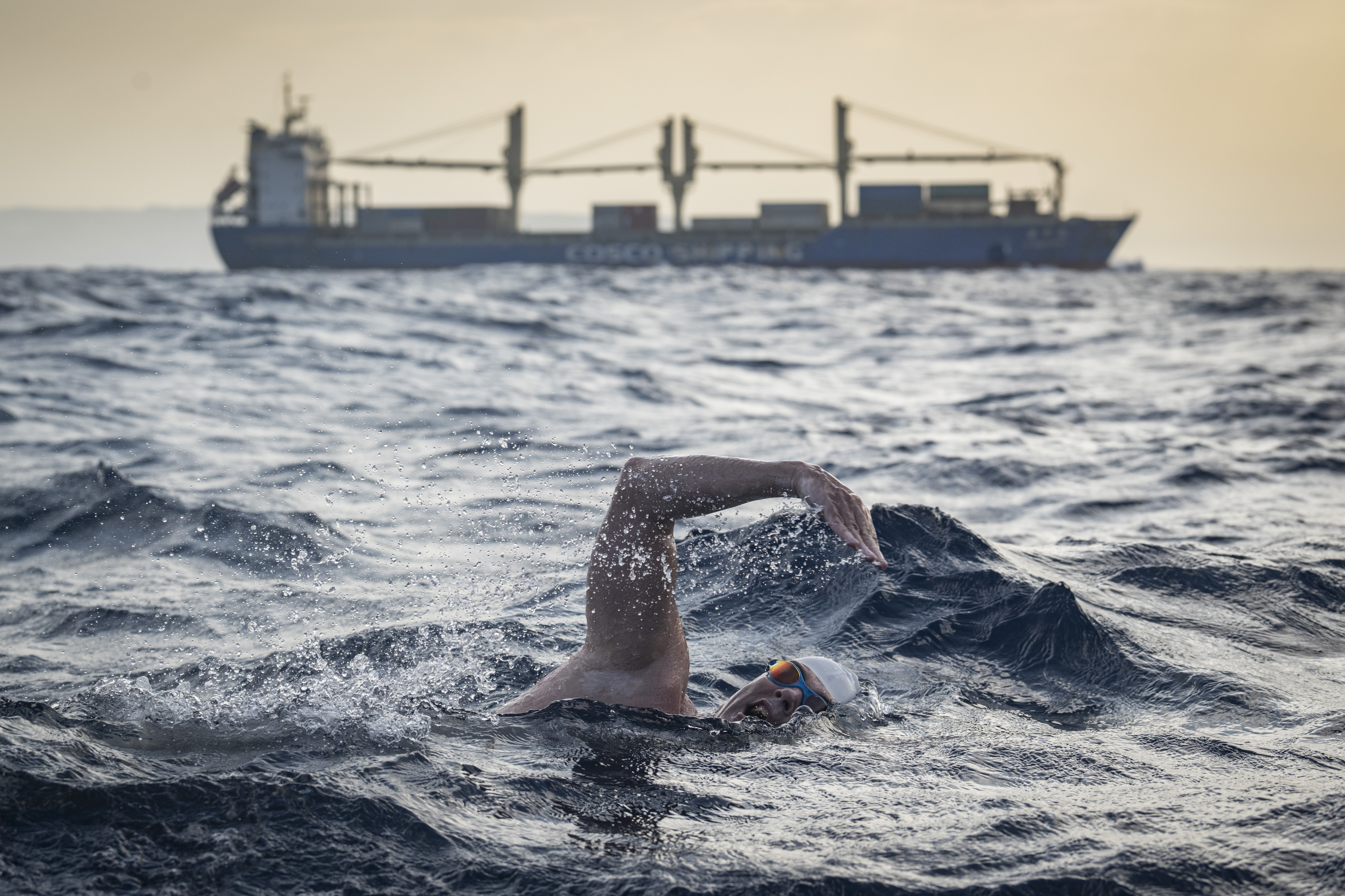Lewis Pugh swimming with a shipping tanker in the background