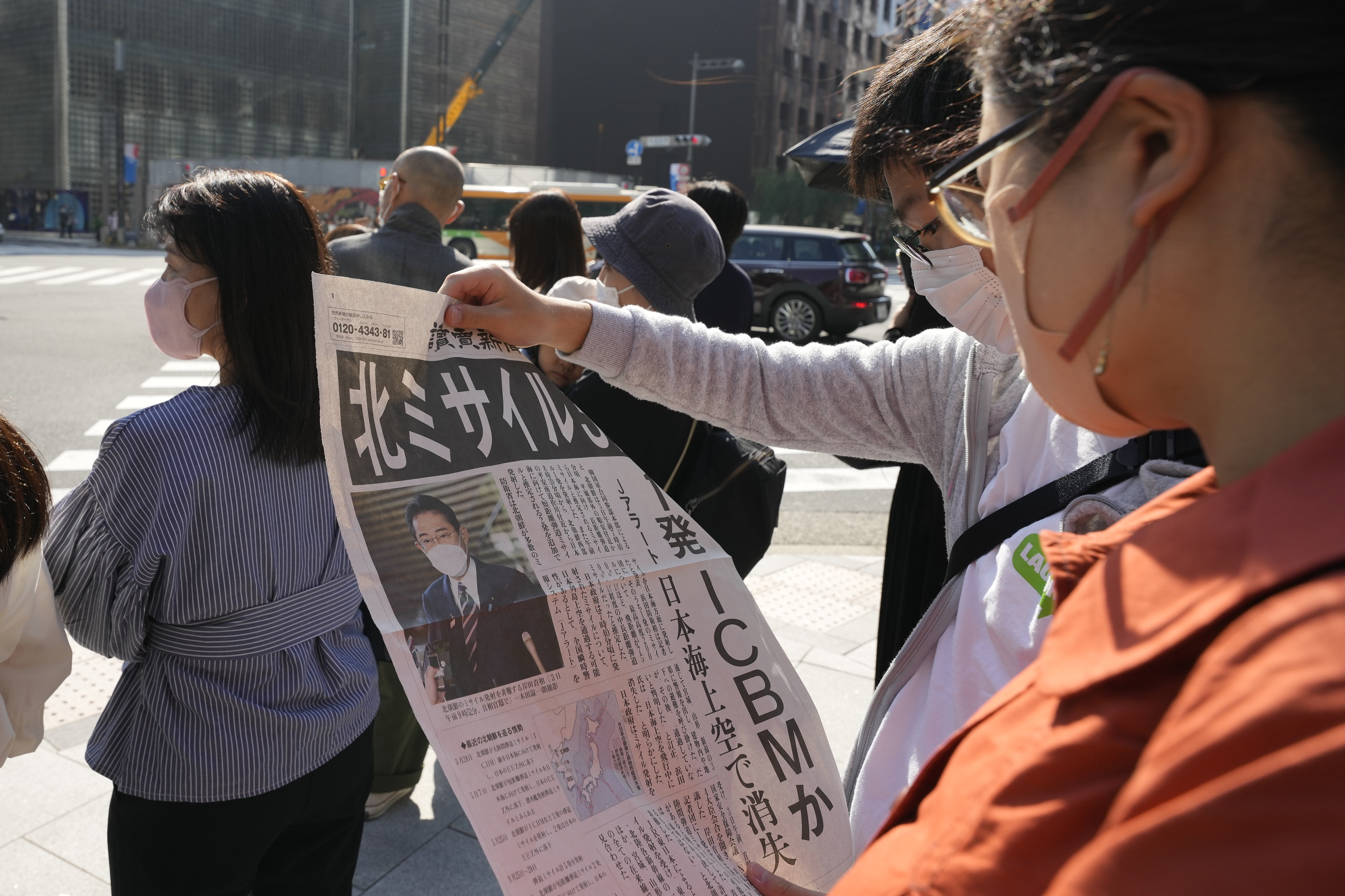 People read an extra edition of Yomiuri newspaper reporting about North Korea's recent missile launches near Japan